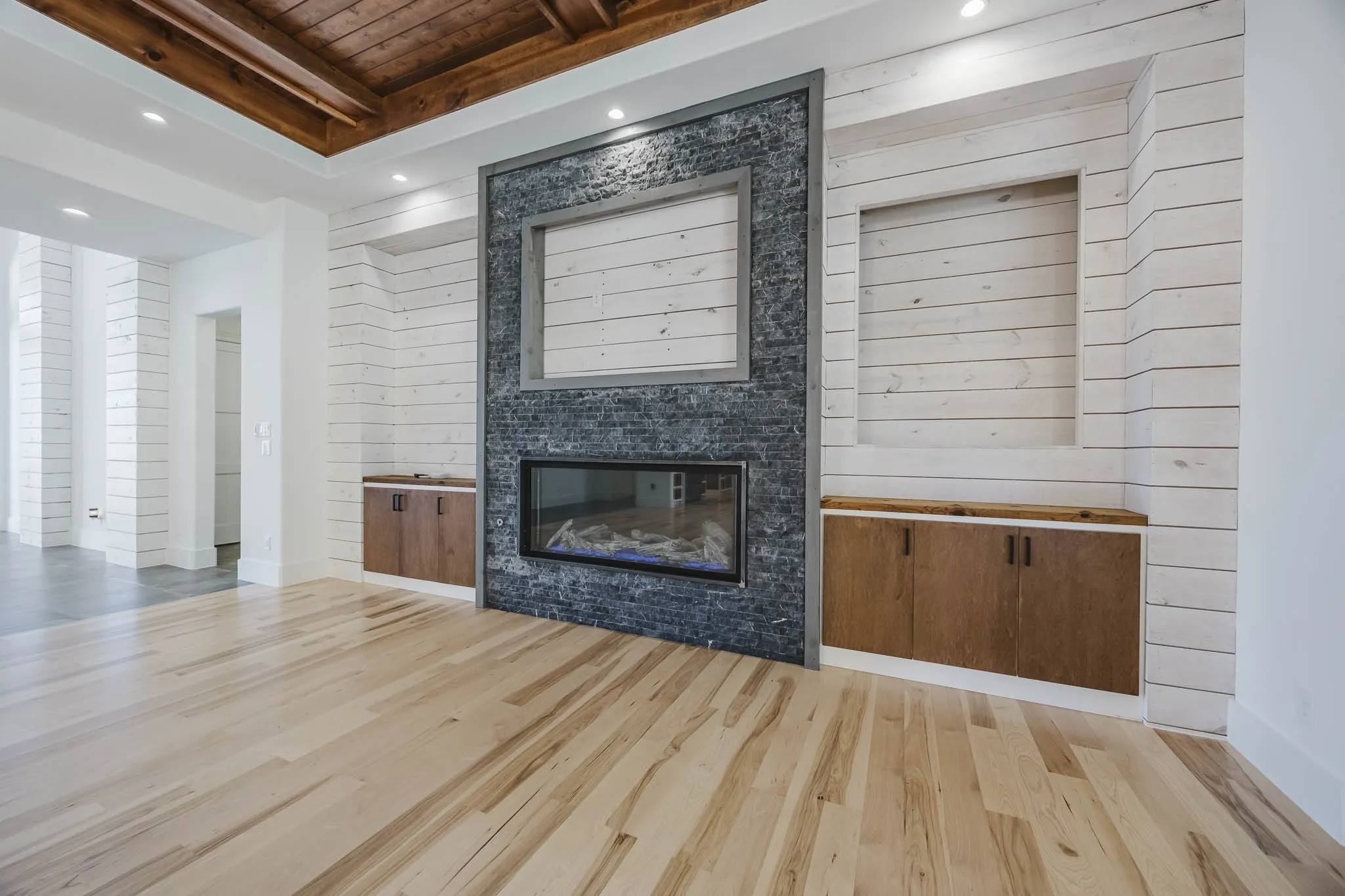 Unfurnished living room featuring recessed lighting, a glass covered fireplace, wood finished floors, and a wooden ceiling with exposed beams