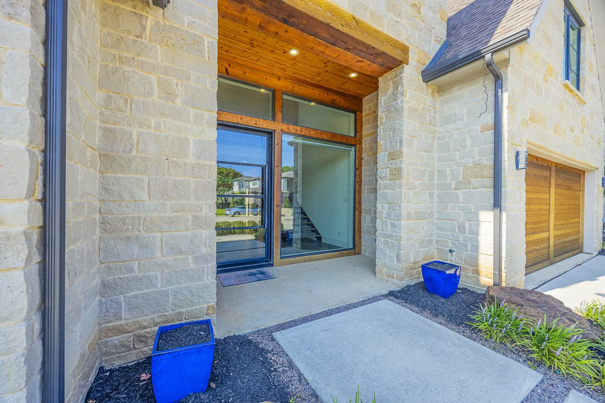 Property entrance featuring a shingled roof and stone siding