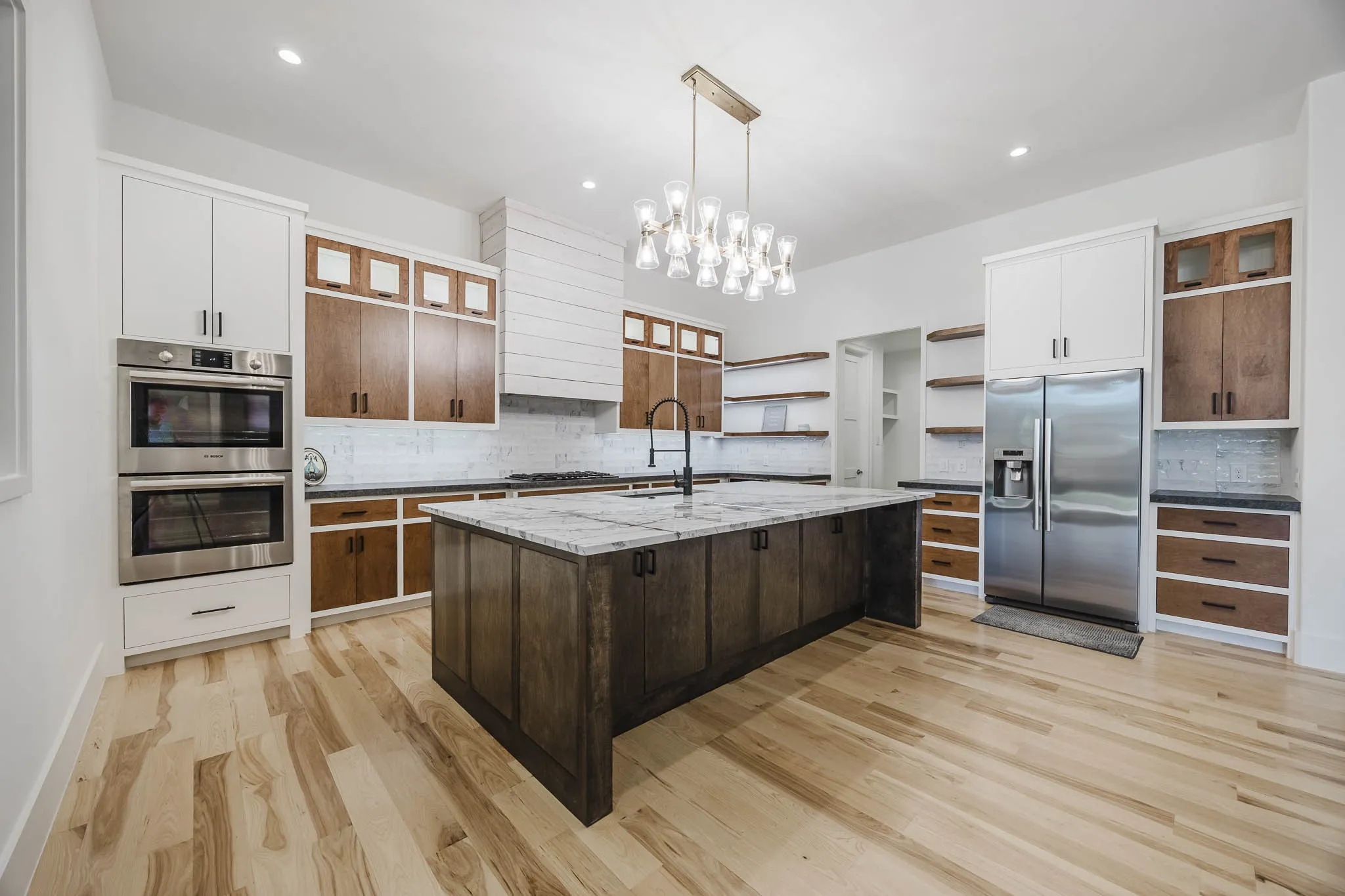 Kitchen with glass insert cabinets, dark brown cabinets, decorative light fixtures, tasteful backsplash, and recessed lighting