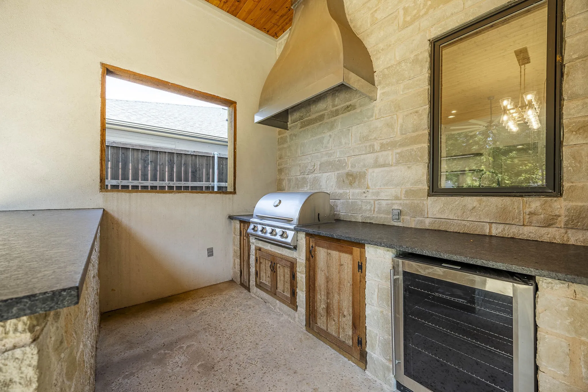 Covered patio with built-in cook station, with vent hood, refrigerator, large food prep and serving counter