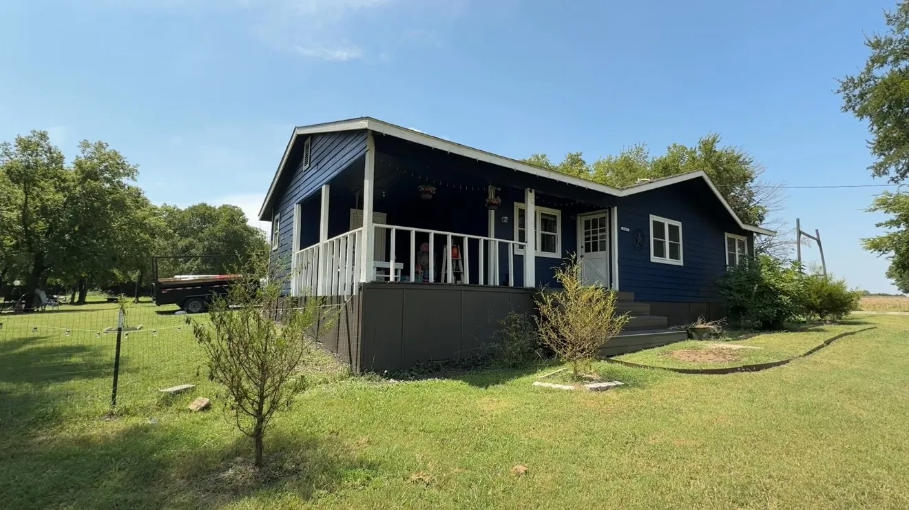 View of property exterior featuring a yard and covered porch