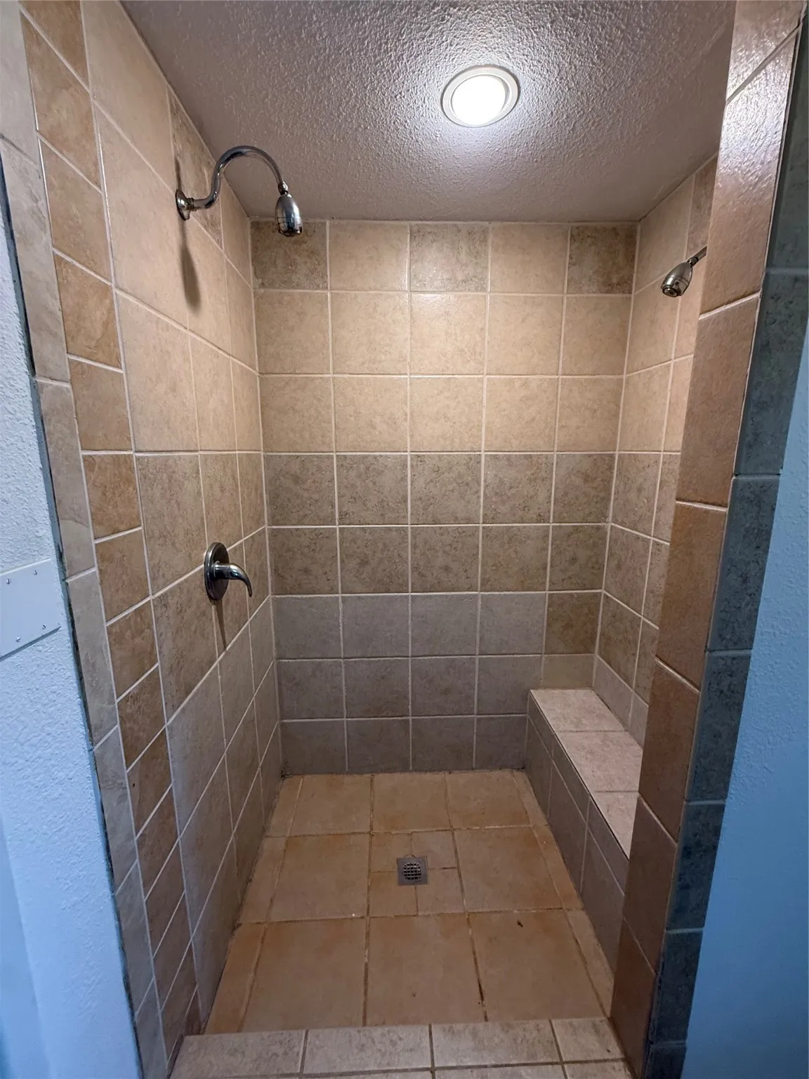Bathroom with a stall shower, a textured ceiling, and light tile patterned floors