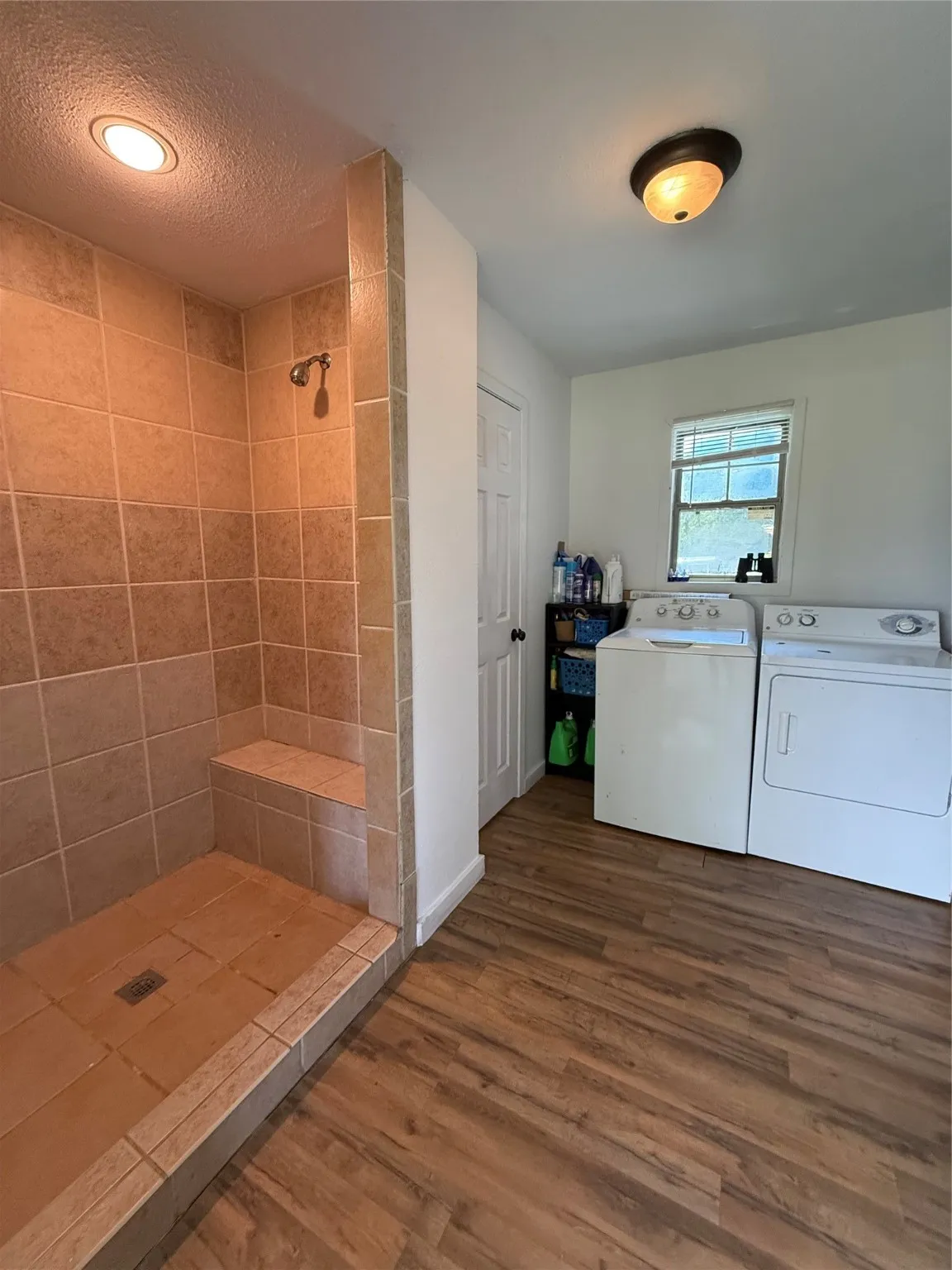 Full bath featuring dark wood-style flooring, a shower stall, separate washer and dryer, and a textured ceiling