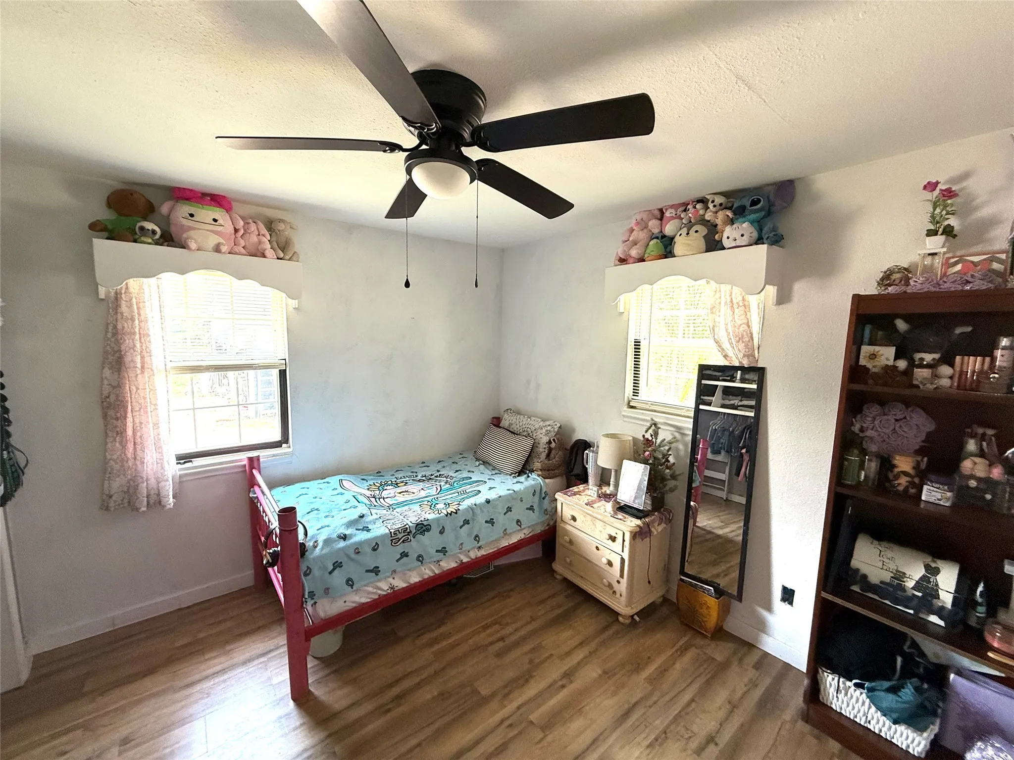 Bedroom with wood finished floors, a textured ceiling, multiple windows, and ceiling fan