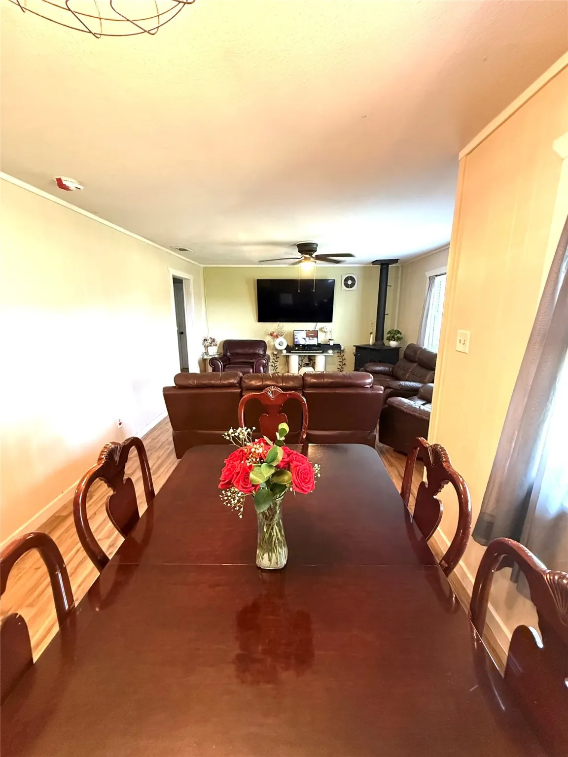 Dining space with a wood stove, wood finished floors, and a ceiling fan