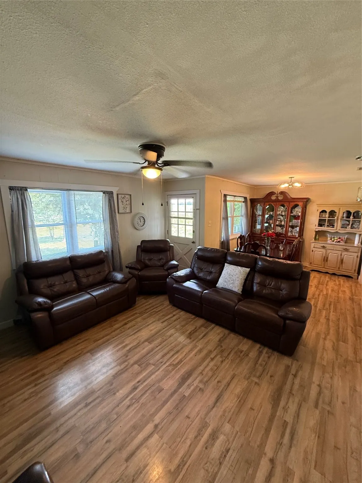 Living area with a textured ceiling, wood finished floors, and ceiling fan