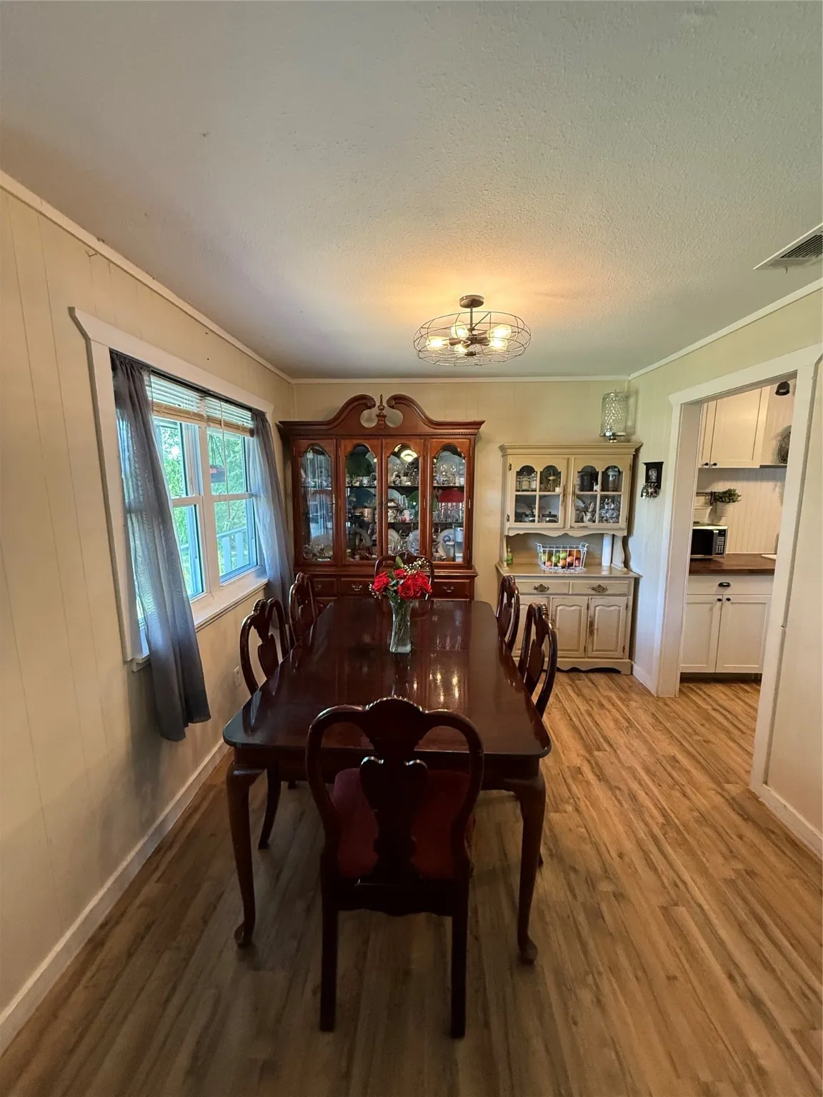 Dining area featuring light wood-style floors, a chandelier, ornamental molding, wooden walls, and a textured ceiling