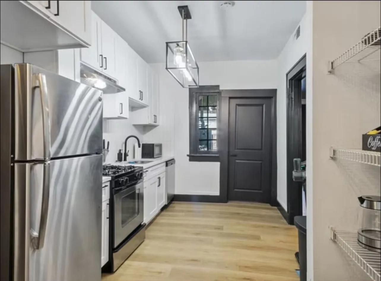 Kitchen featuring stainless steel appliances, white cabinetry, light wood-style floors, light countertops, and decorative light fixtures