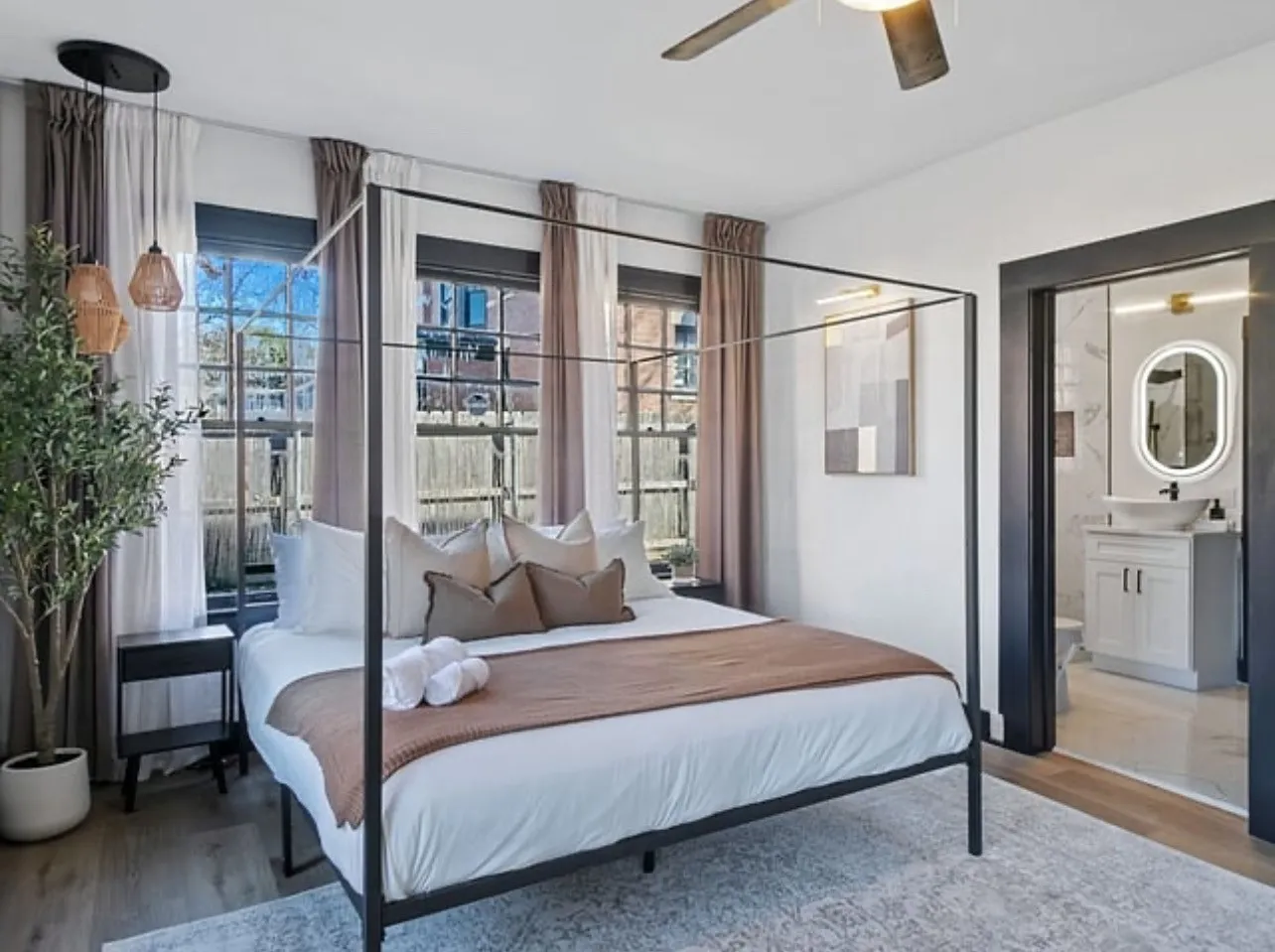 Bedroom with wood finished floors, ensuite bathroom, and a ceiling fan