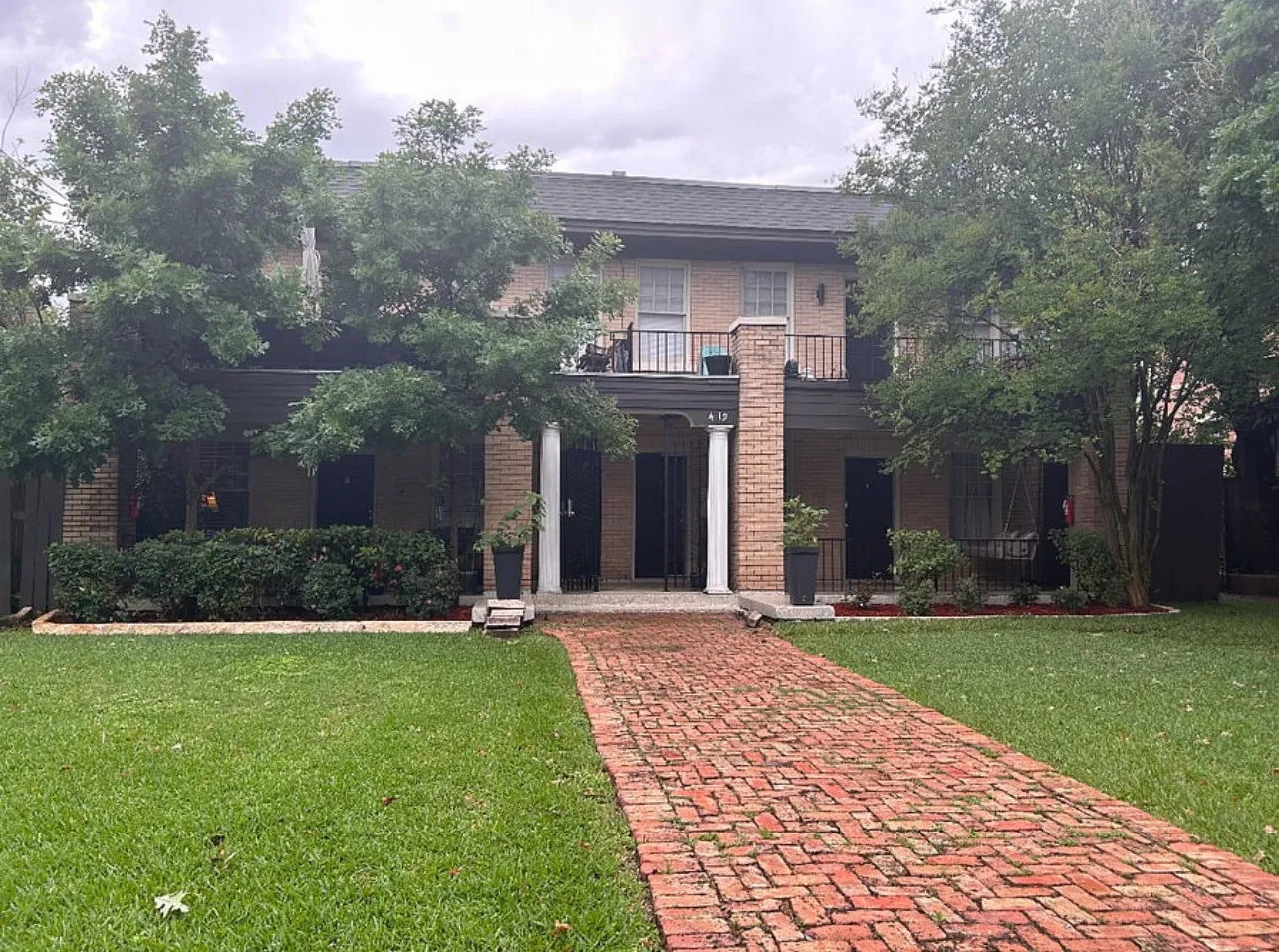 View of front facade featuring brick siding, a front lawn, and a balcony