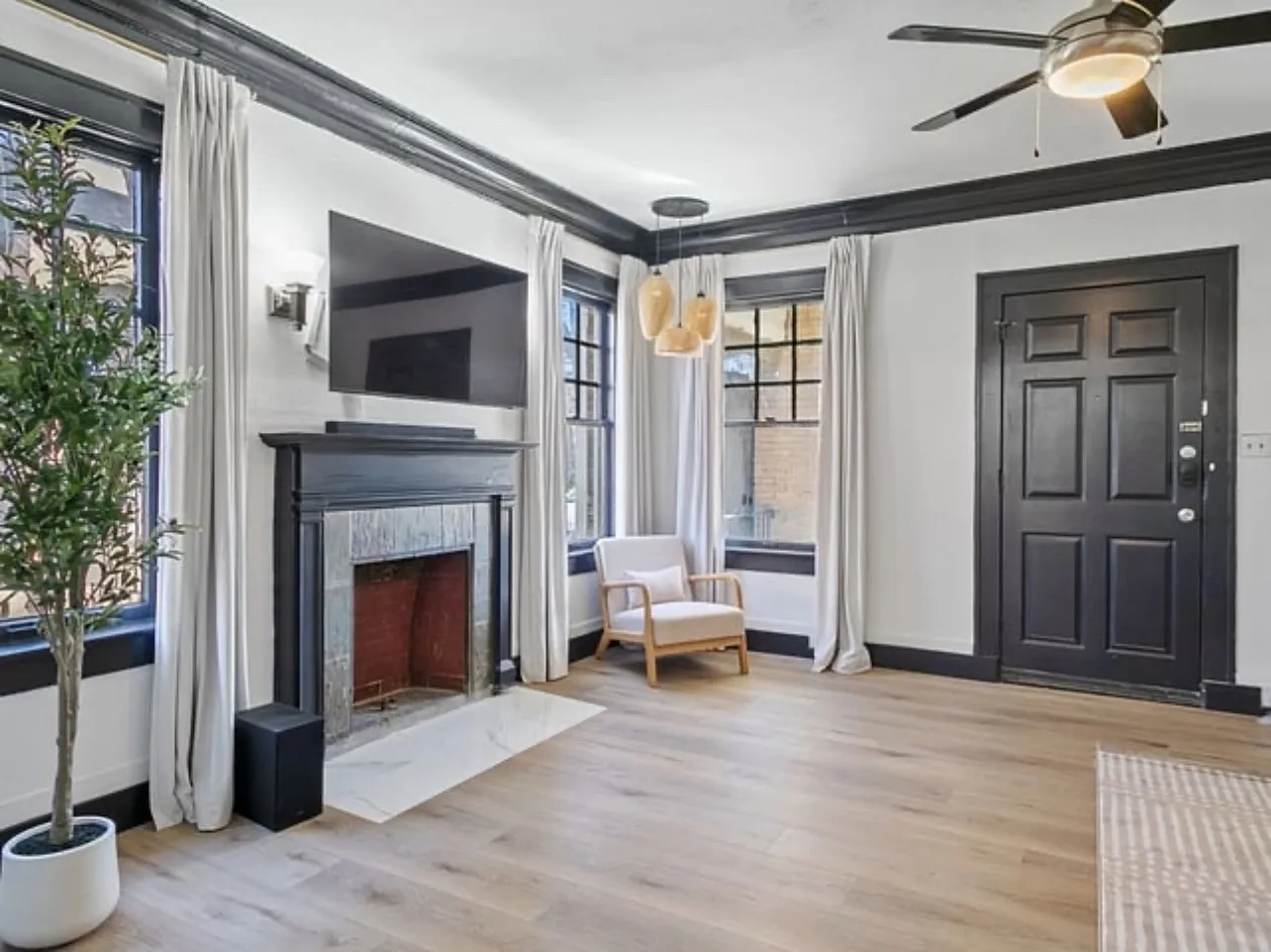 Living area with light wood finished floors, ornamental molding, a premium fireplace, and a ceiling fan