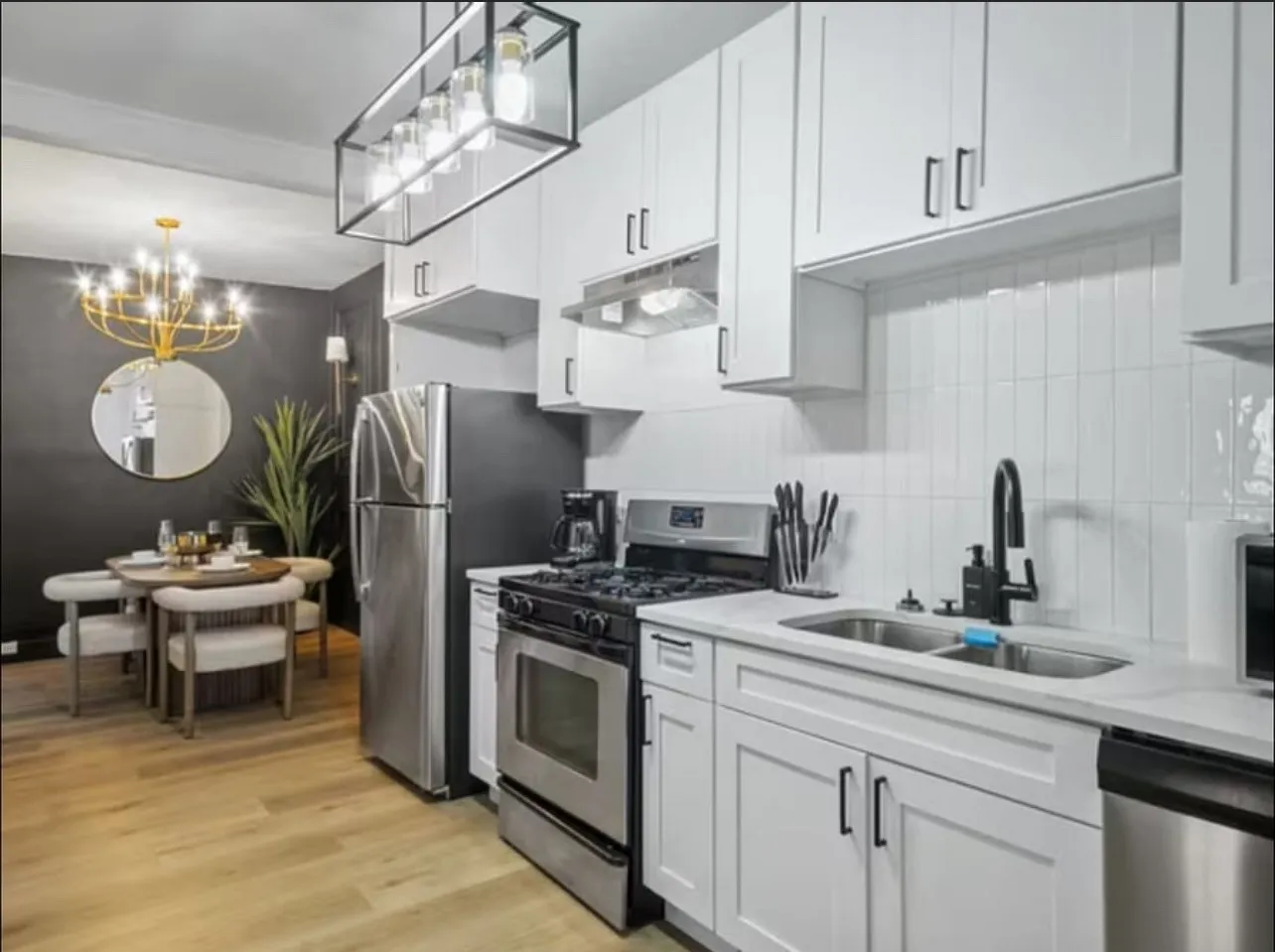 Kitchen with appliances with stainless steel finishes, hanging light fixtures, light wood finished floors, and under cabinet range hood