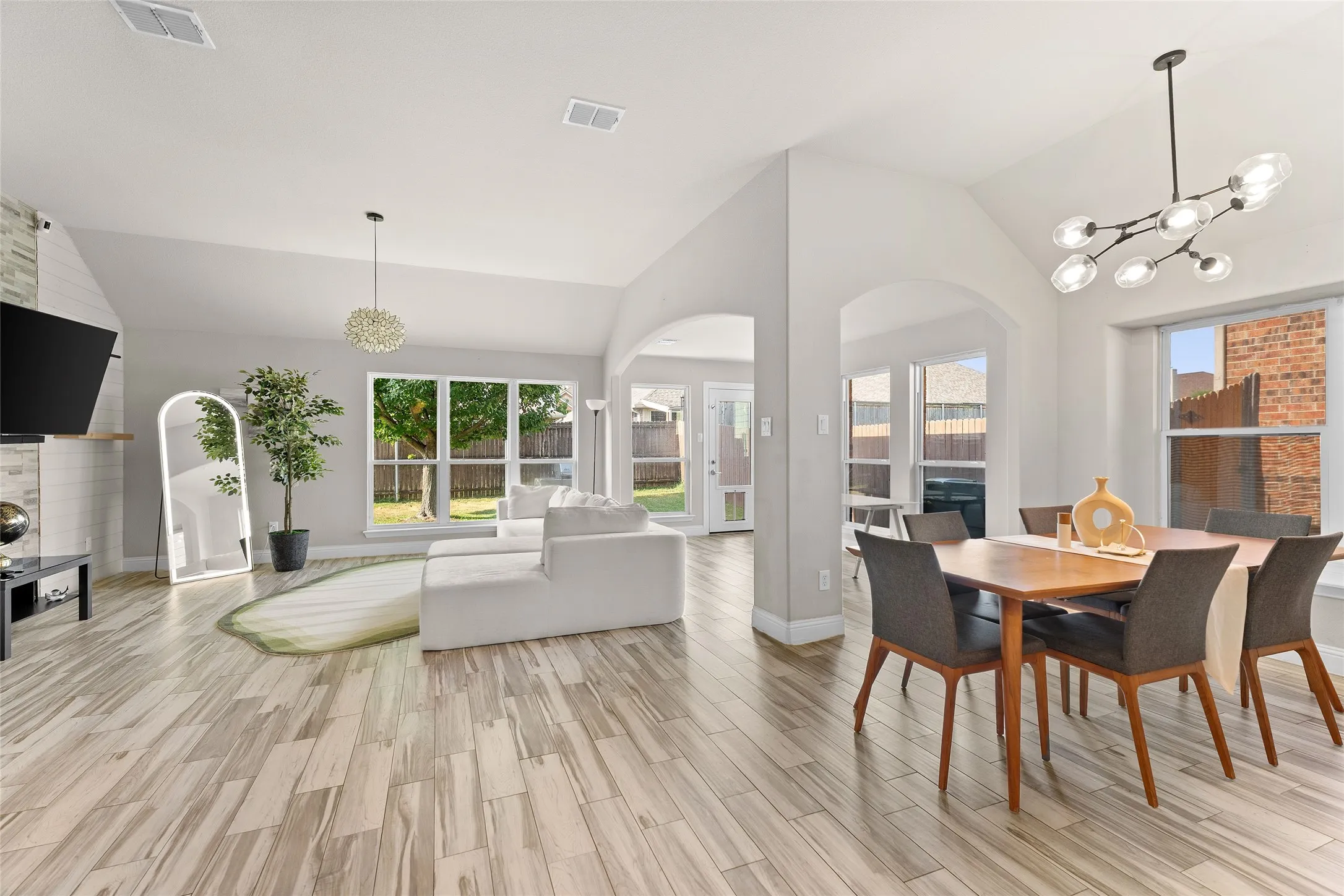 Dining space featuring a chandelier, arched walkways, light wood-style flooring, and high vaulted ceiling