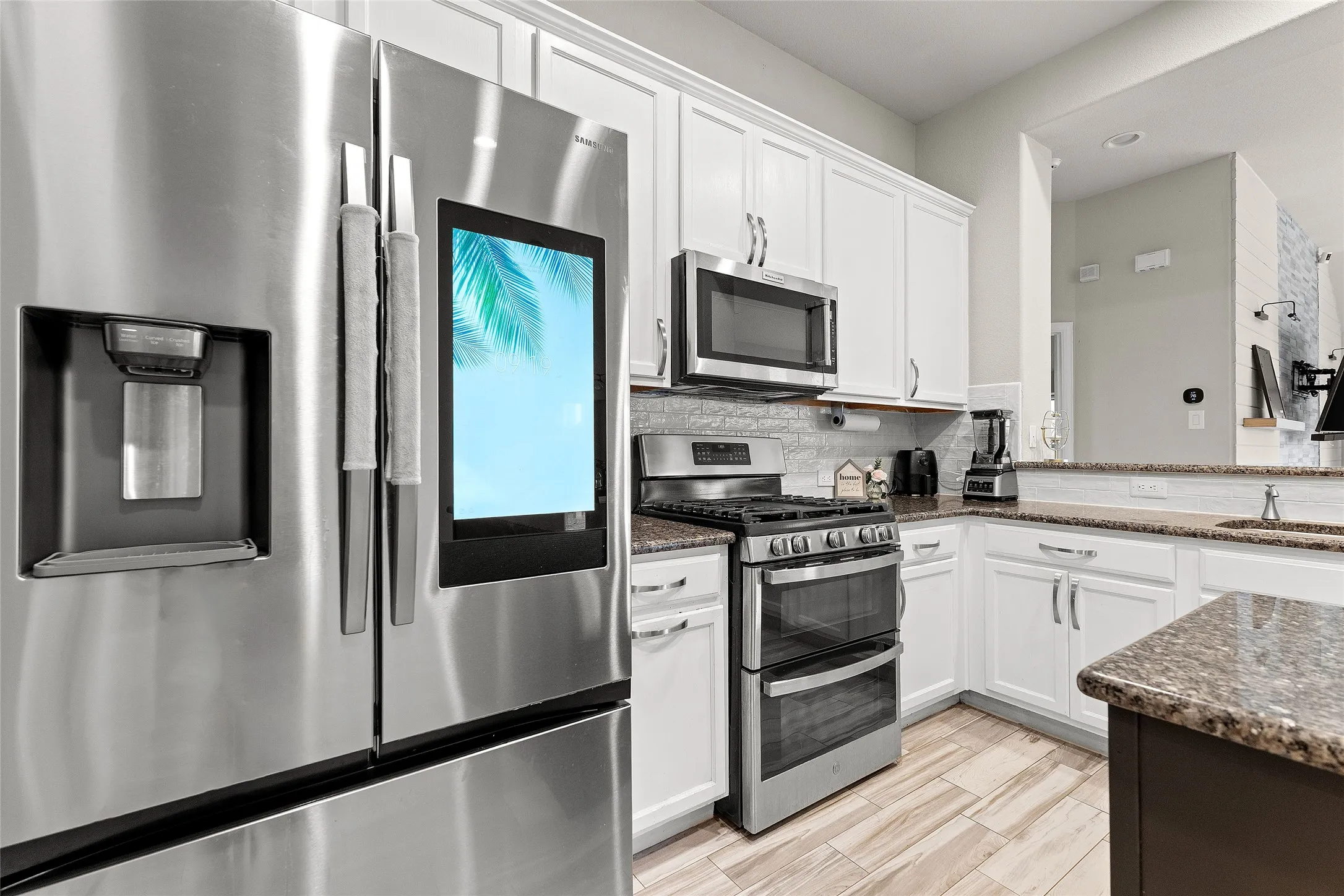 Kitchen featuring appliances with stainless steel finishes, backsplash, white cabinetry, and dark stone counters
