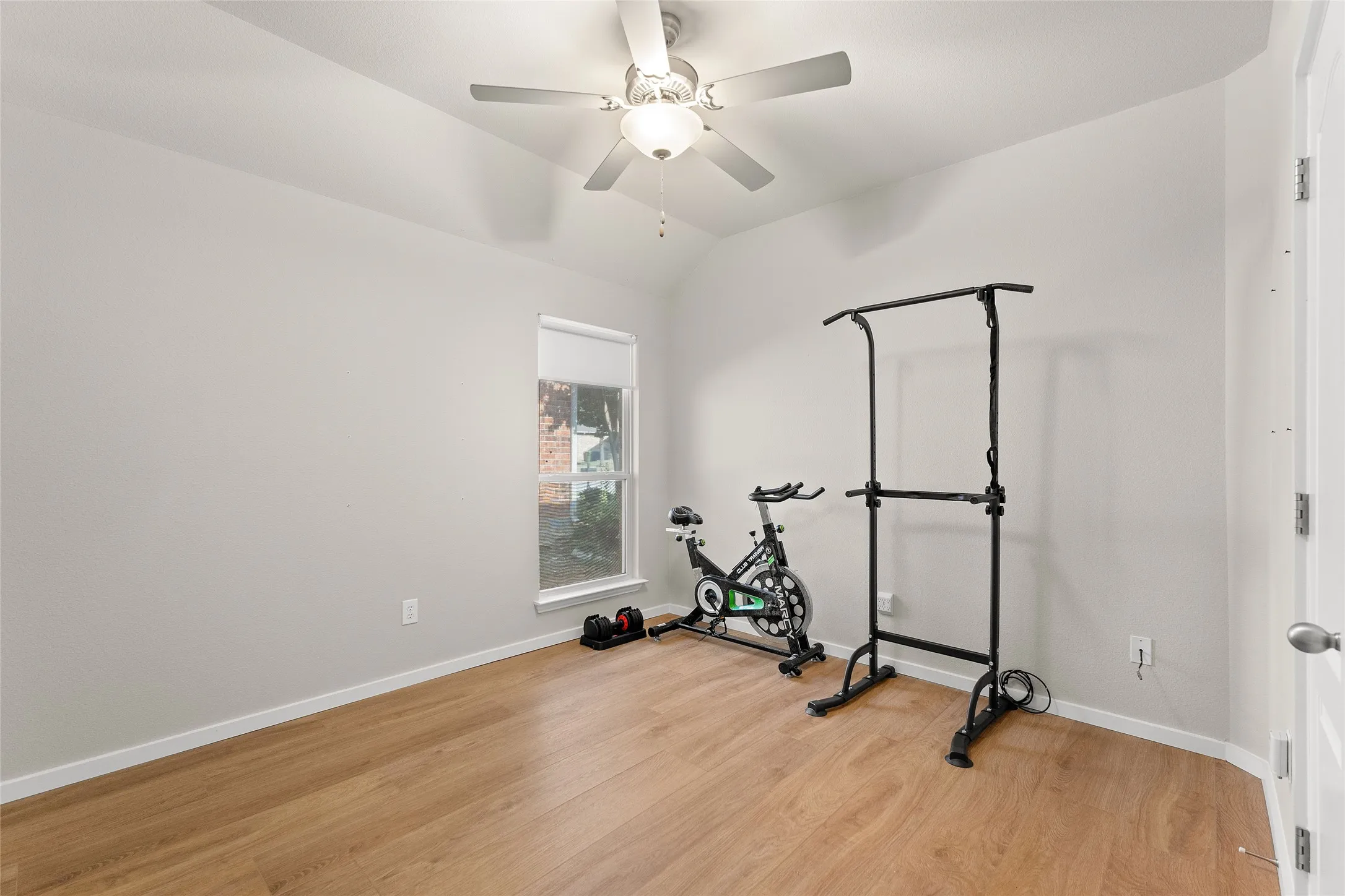 Workout area with light wood-type flooring, lofted ceiling, and ceiling fan