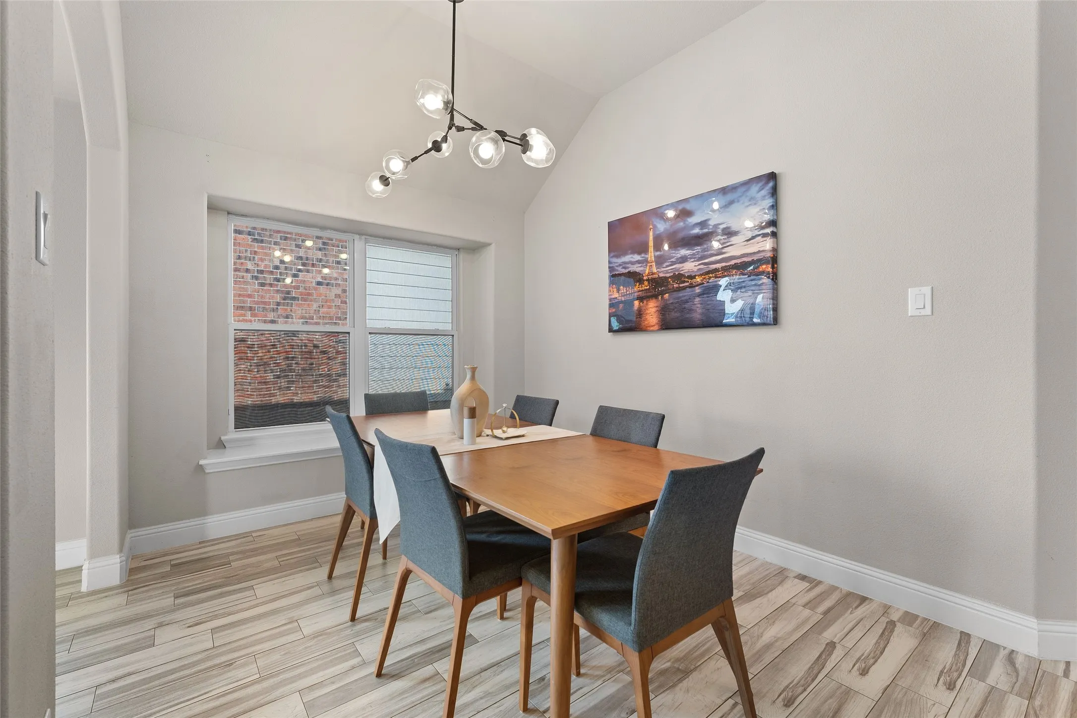Dining space with light wood-type flooring, vaulted ceiling, and a chandelier