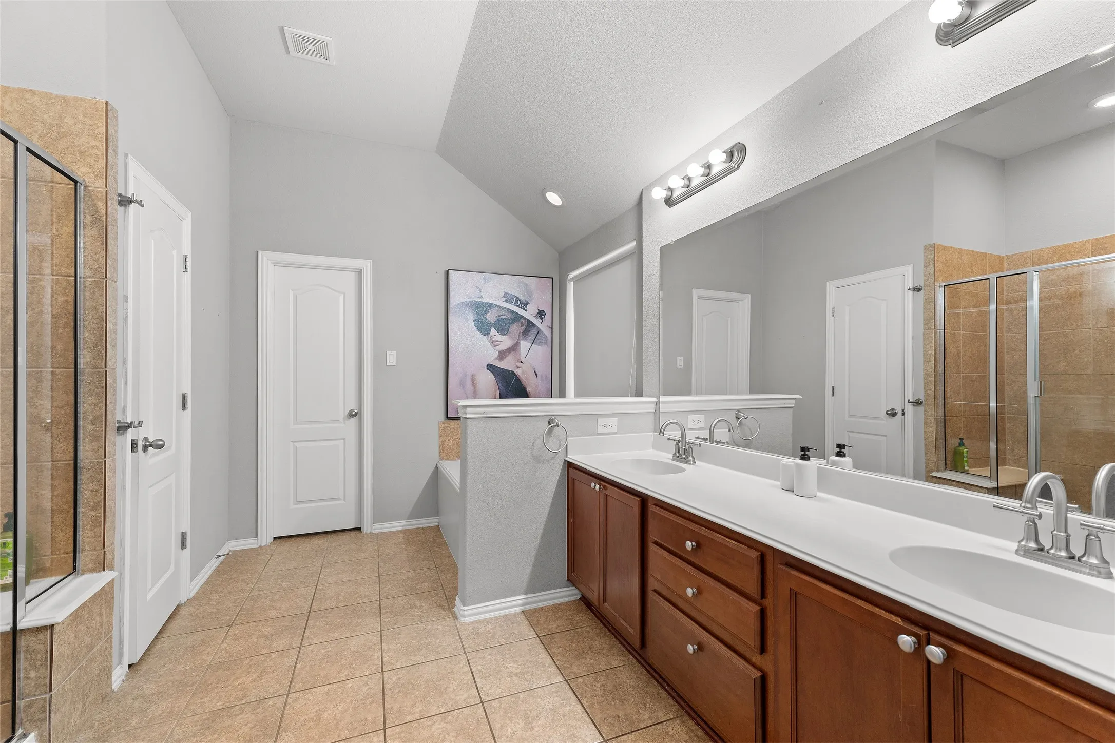 Bathroom with a stall shower, light tile patterned flooring, a garden tub, double vanity, and lofted ceiling
