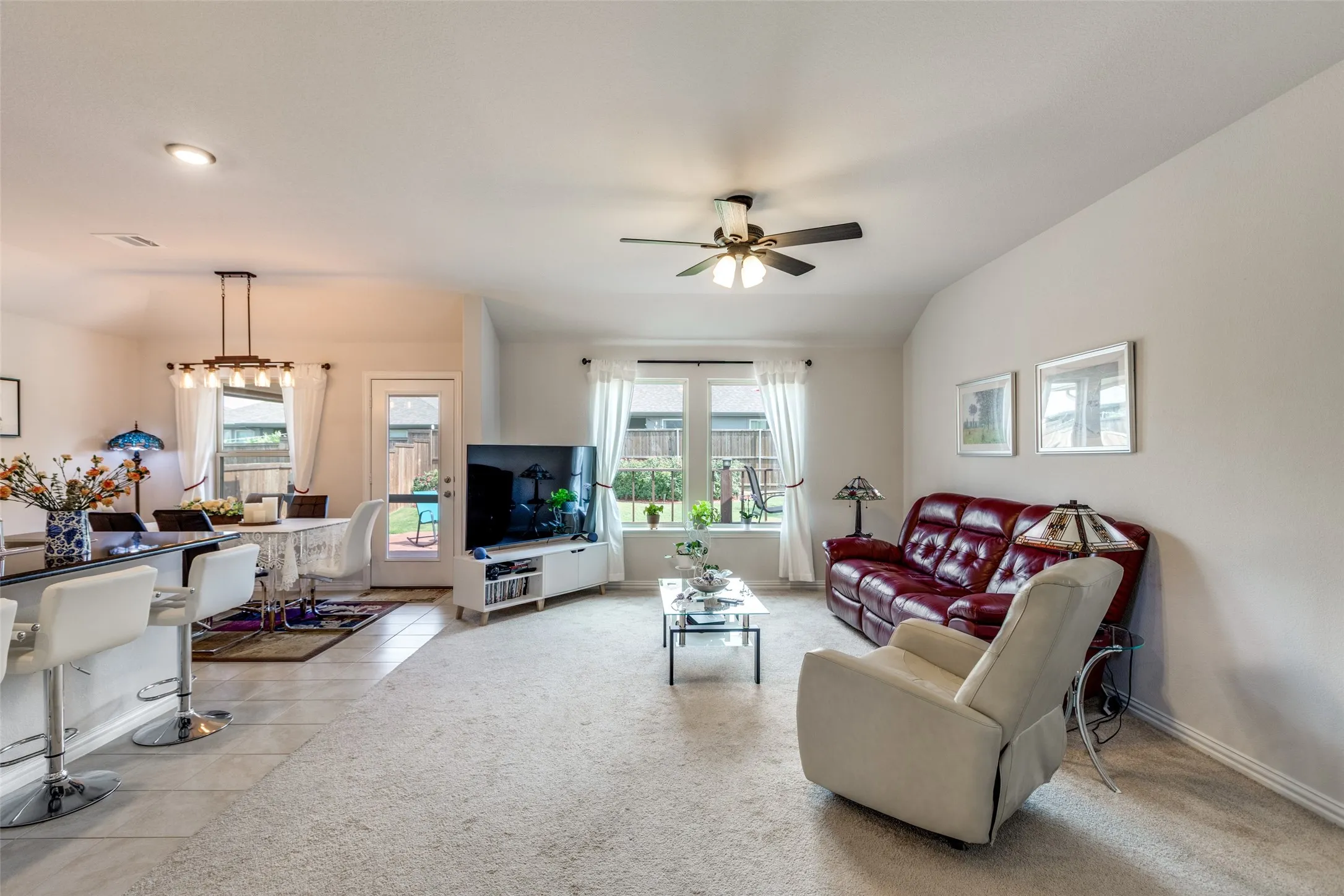Living room featuring plenty of natural light, light carpet, a ceiling fan, and light tile patterned floors