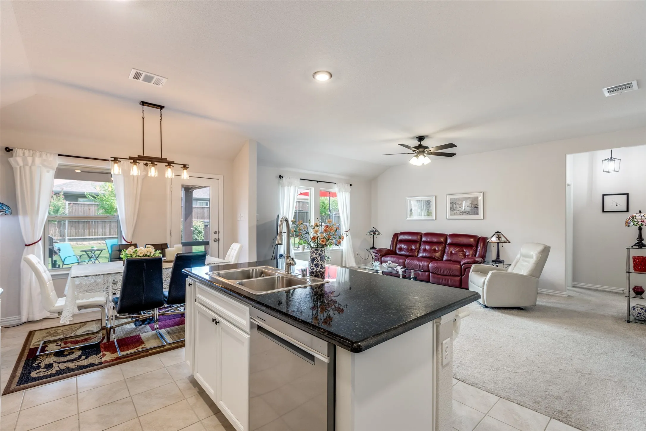 Kitchen with pendant lighting, open floor plan, white cabinets, stainless steel dishwasher, and a kitchen island with sink