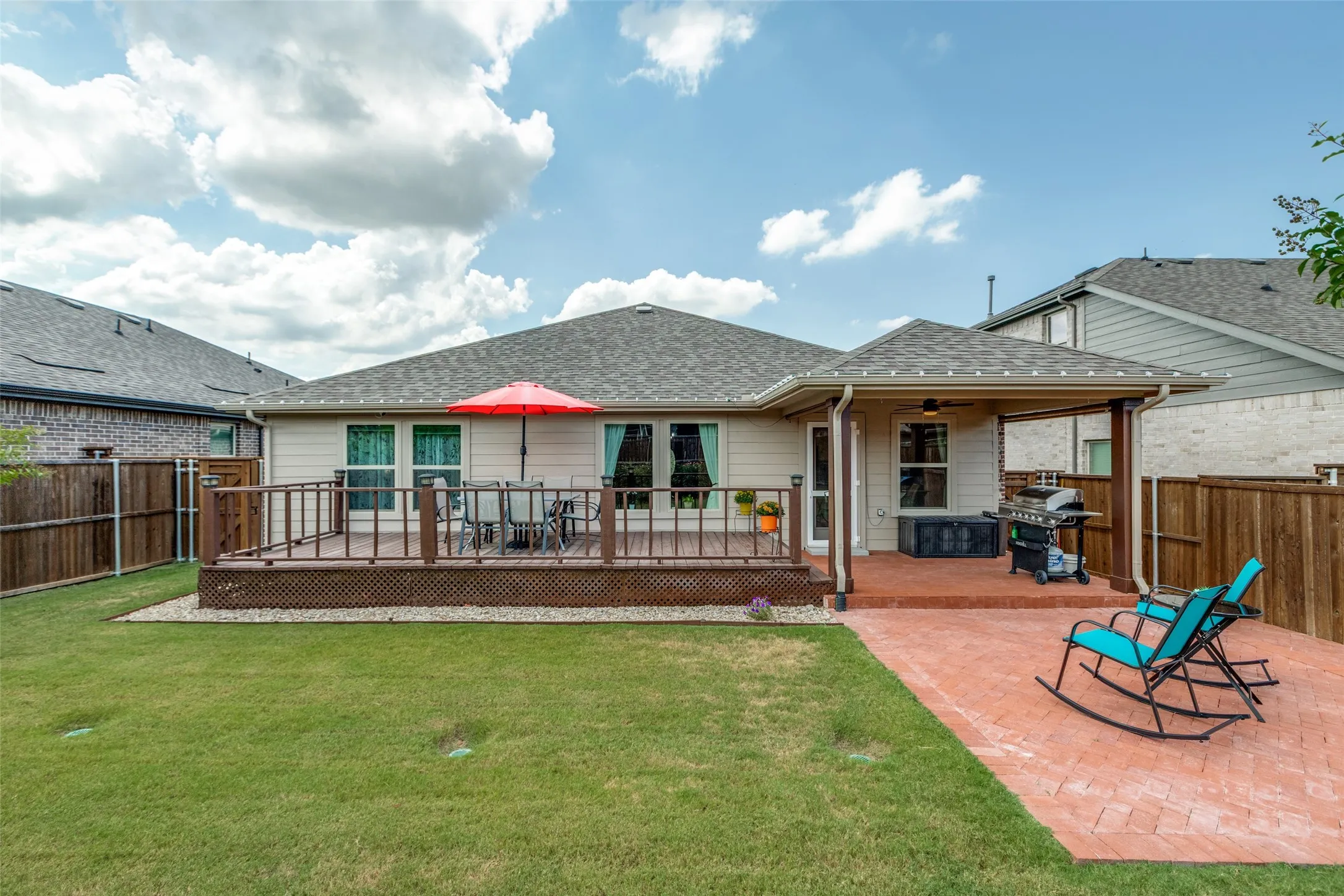 Back of house featuring roof with shingles, a fenced backyard, a wooden deck, and a patio
