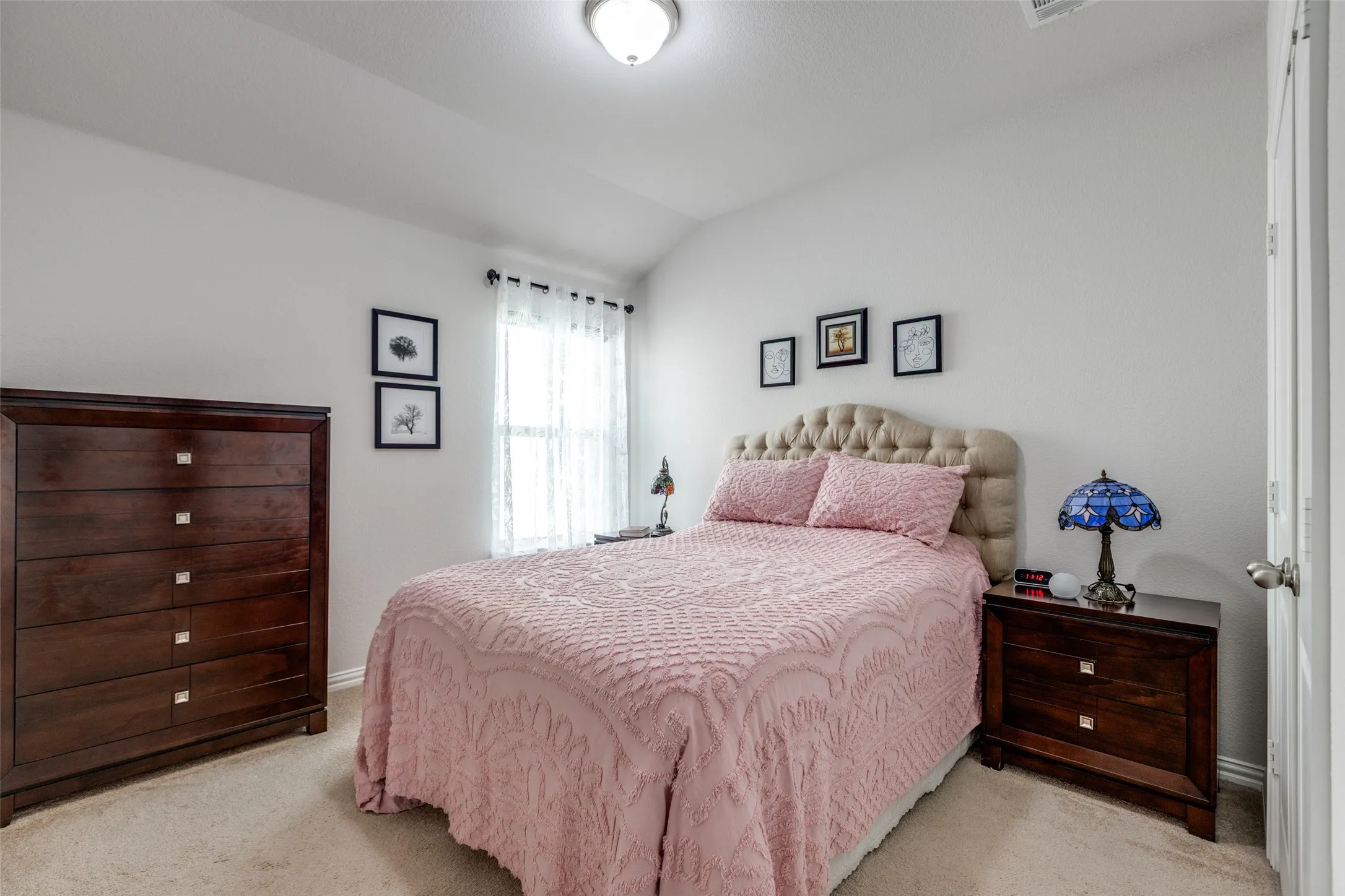 Bedroom featuring light carpet and vaulted ceiling