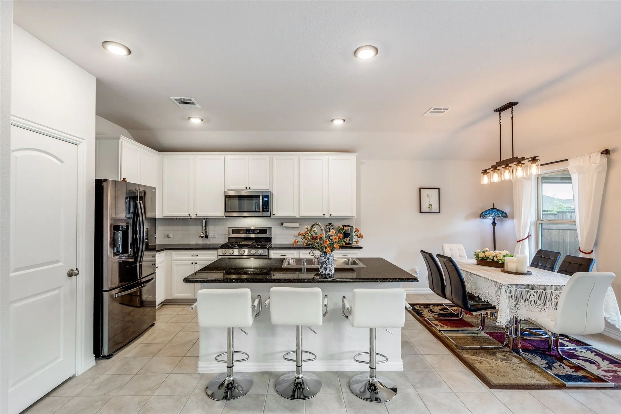 Kitchen featuring tasteful backsplash, appliances with stainless steel finishes, an island with sink, dark stone counters, and a breakfast bar