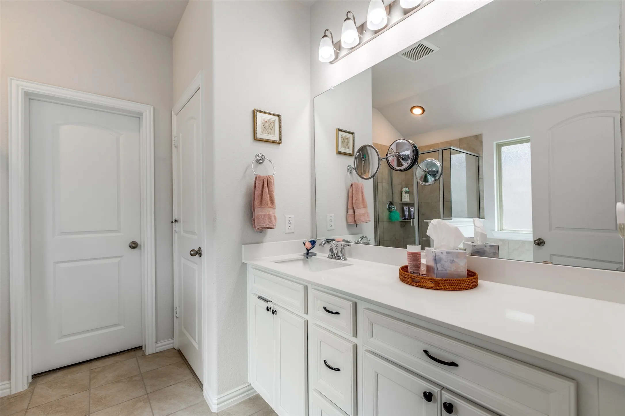 Bathroom with a shower stall, vanity, light tile patterned flooring, and lofted ceiling