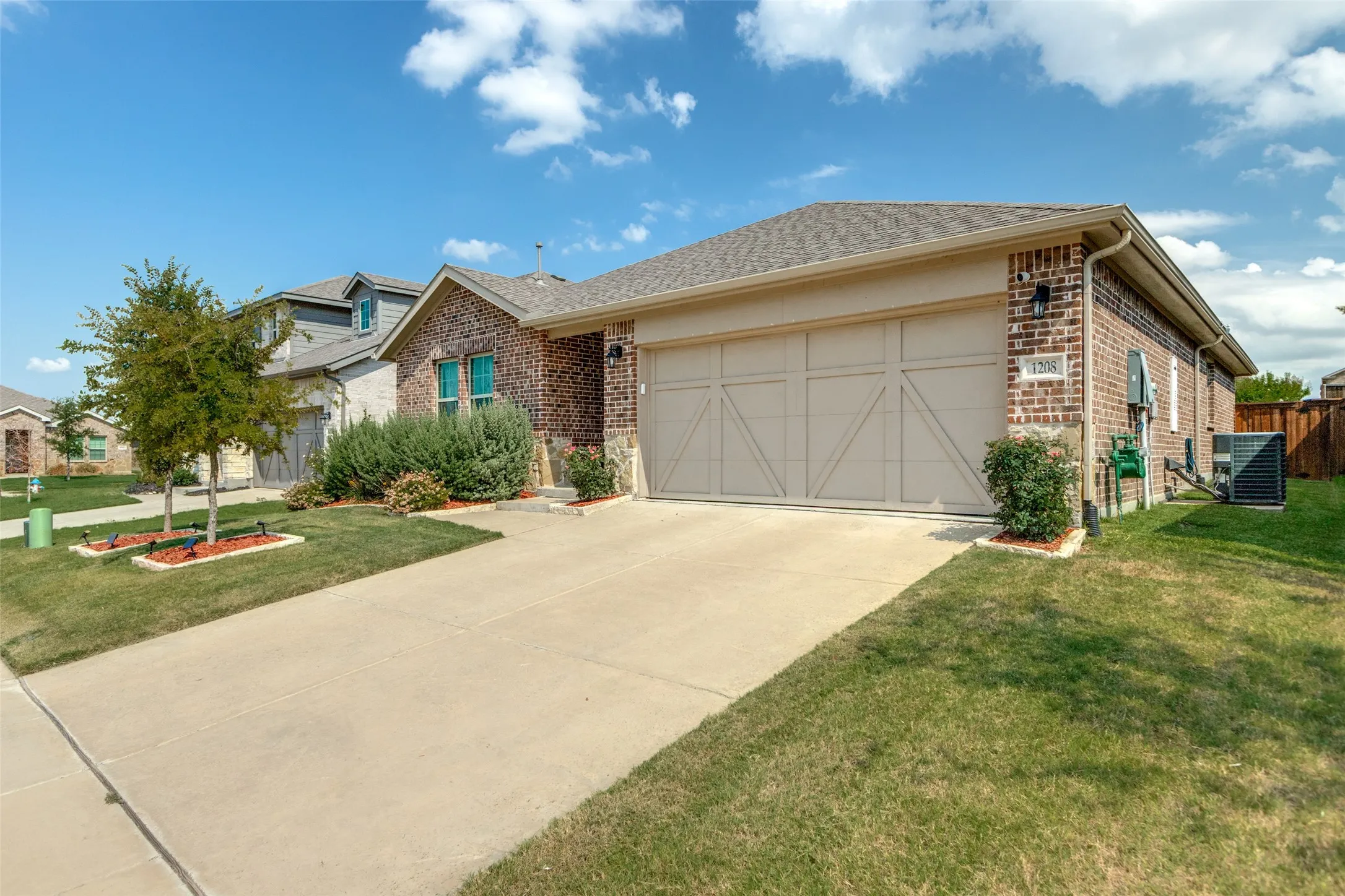 Ranch-style home featuring brick siding, driveway, an attached garage, a front yard, and roof with shingles
