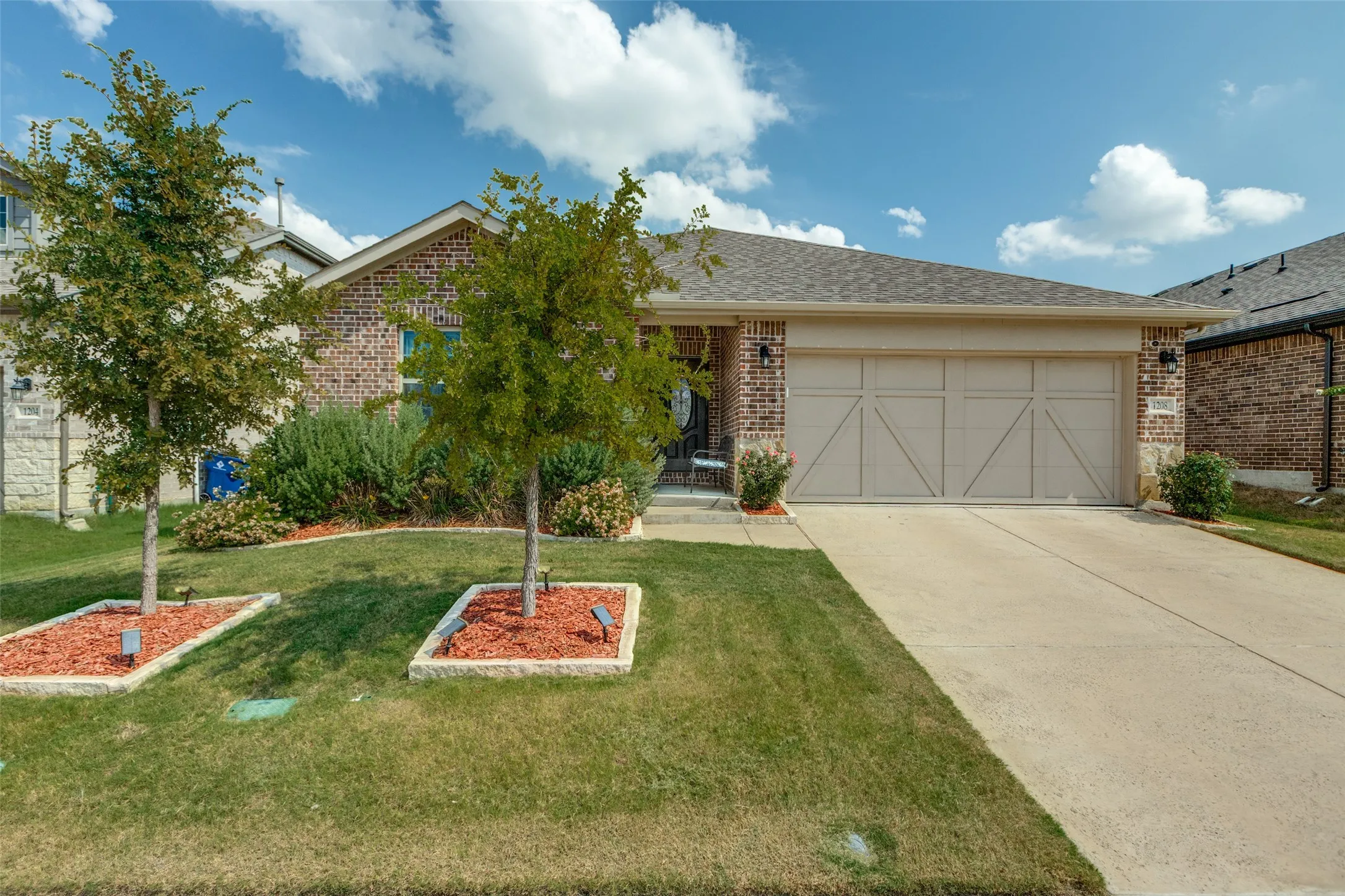 View of front of home featuring a garage, concrete driveway, brick siding, a front lawn, and roof with shingles