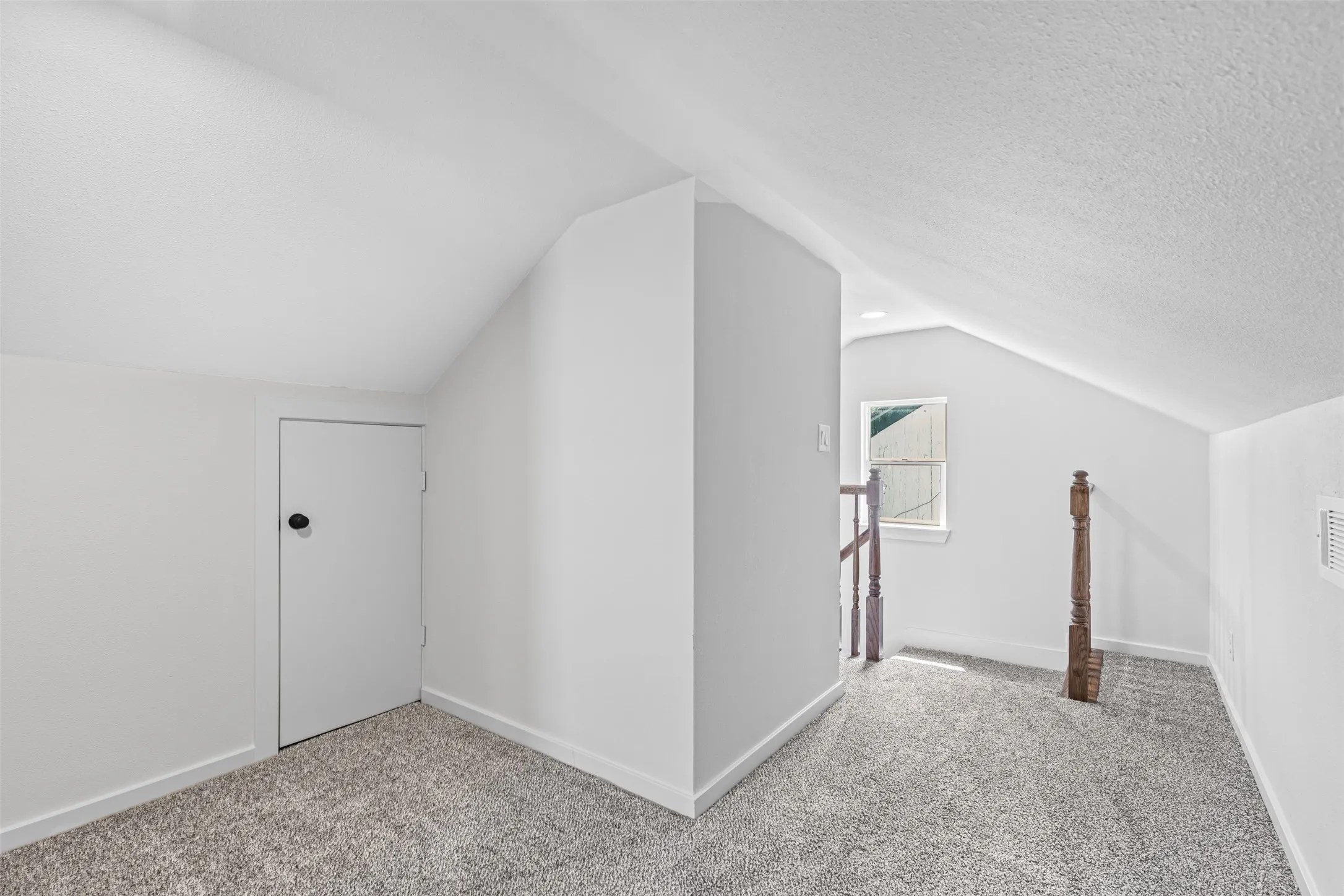 Additional living space with carpet floors, vaulted ceiling, and a textured ceiling