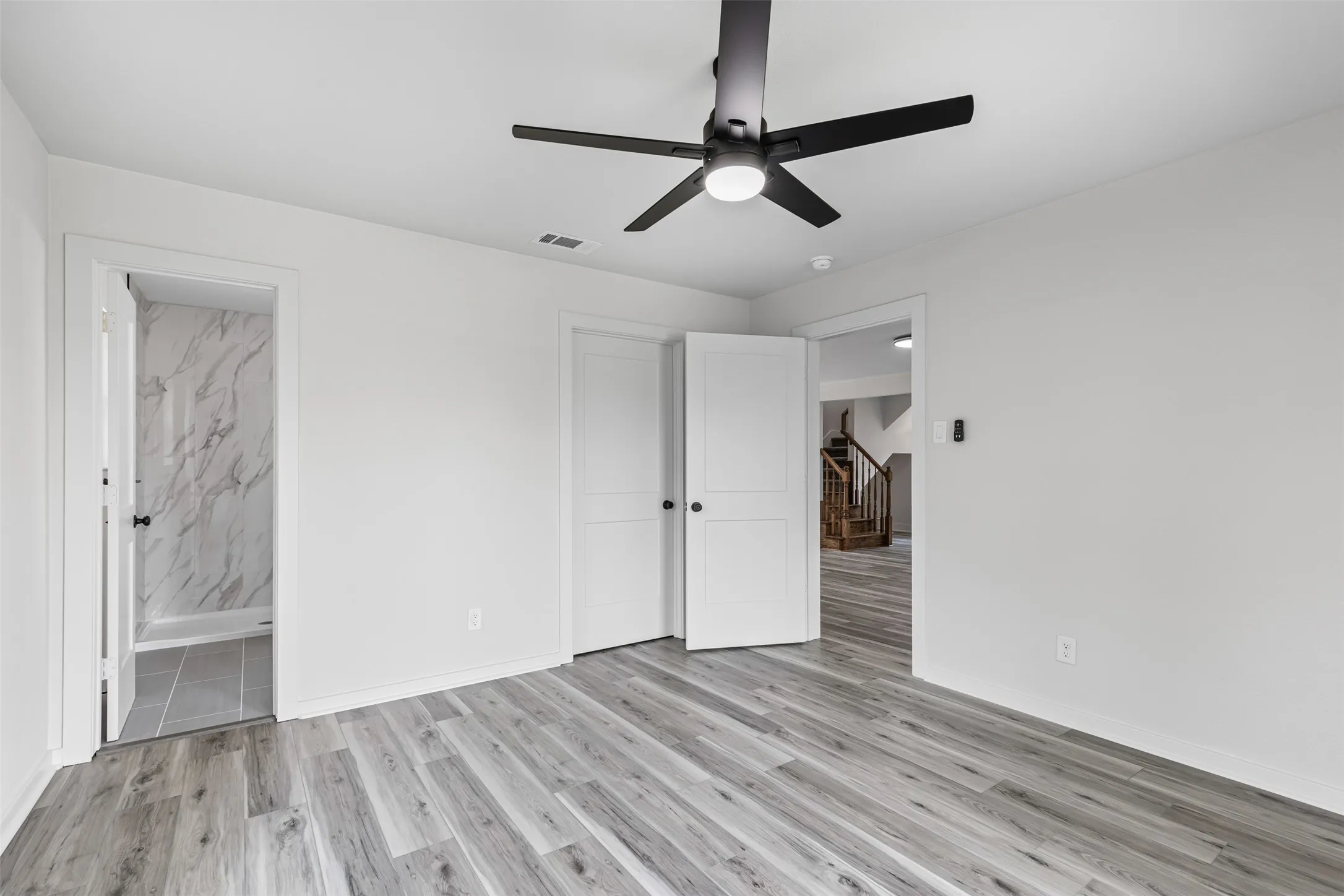 Unfurnished bedroom featuring light wood-type flooring, a ceiling fan, and connected bathroom