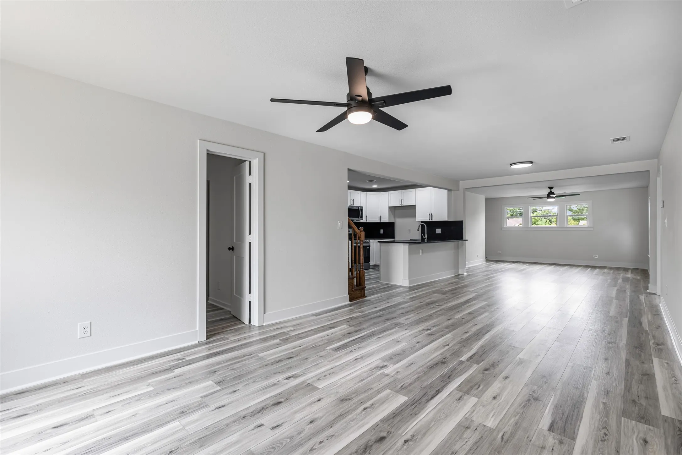 Unfurnished living room with light wood finished floors and ceiling fan