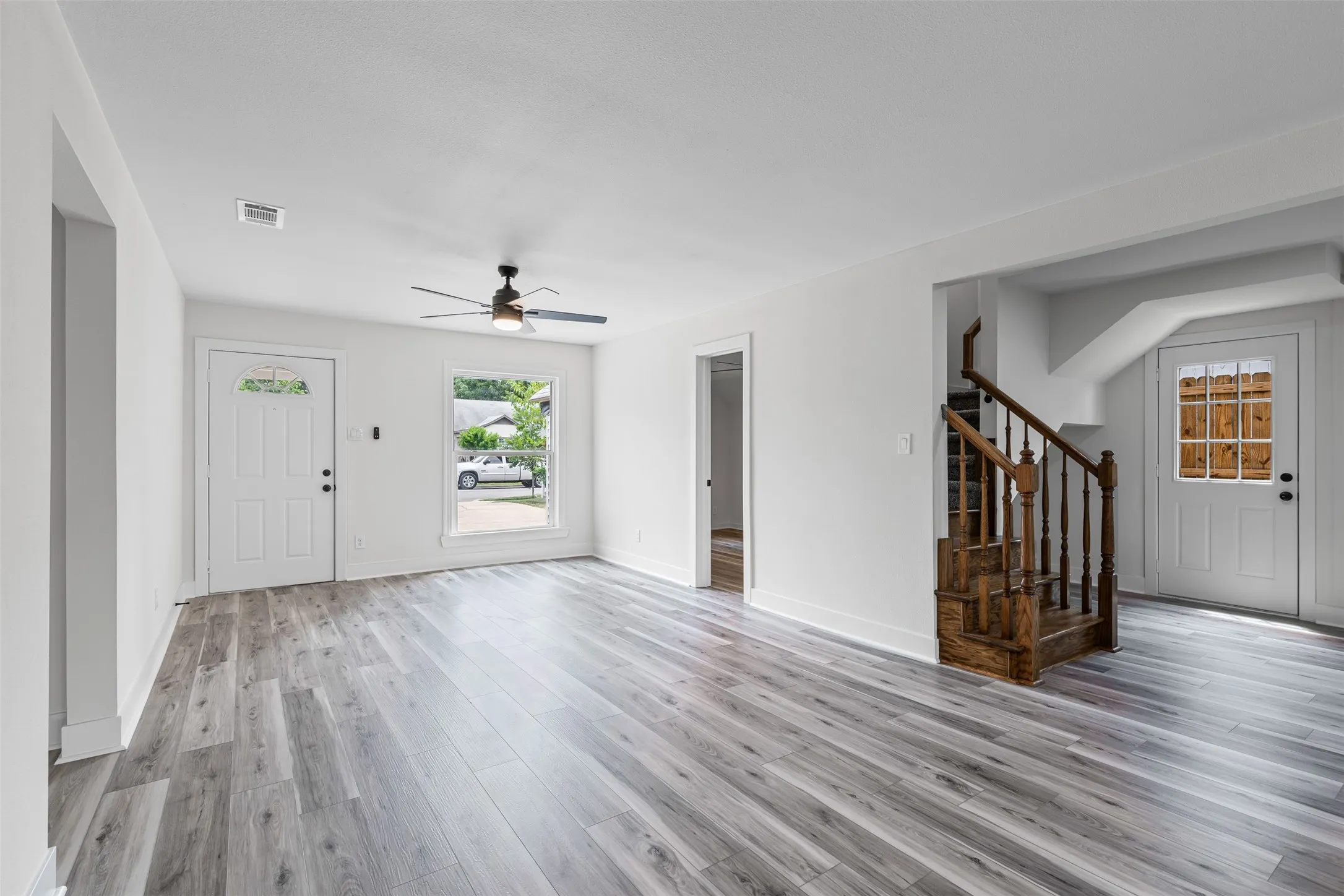 Foyer entrance featuring light wood-type flooring, stairway, and ceiling fan
