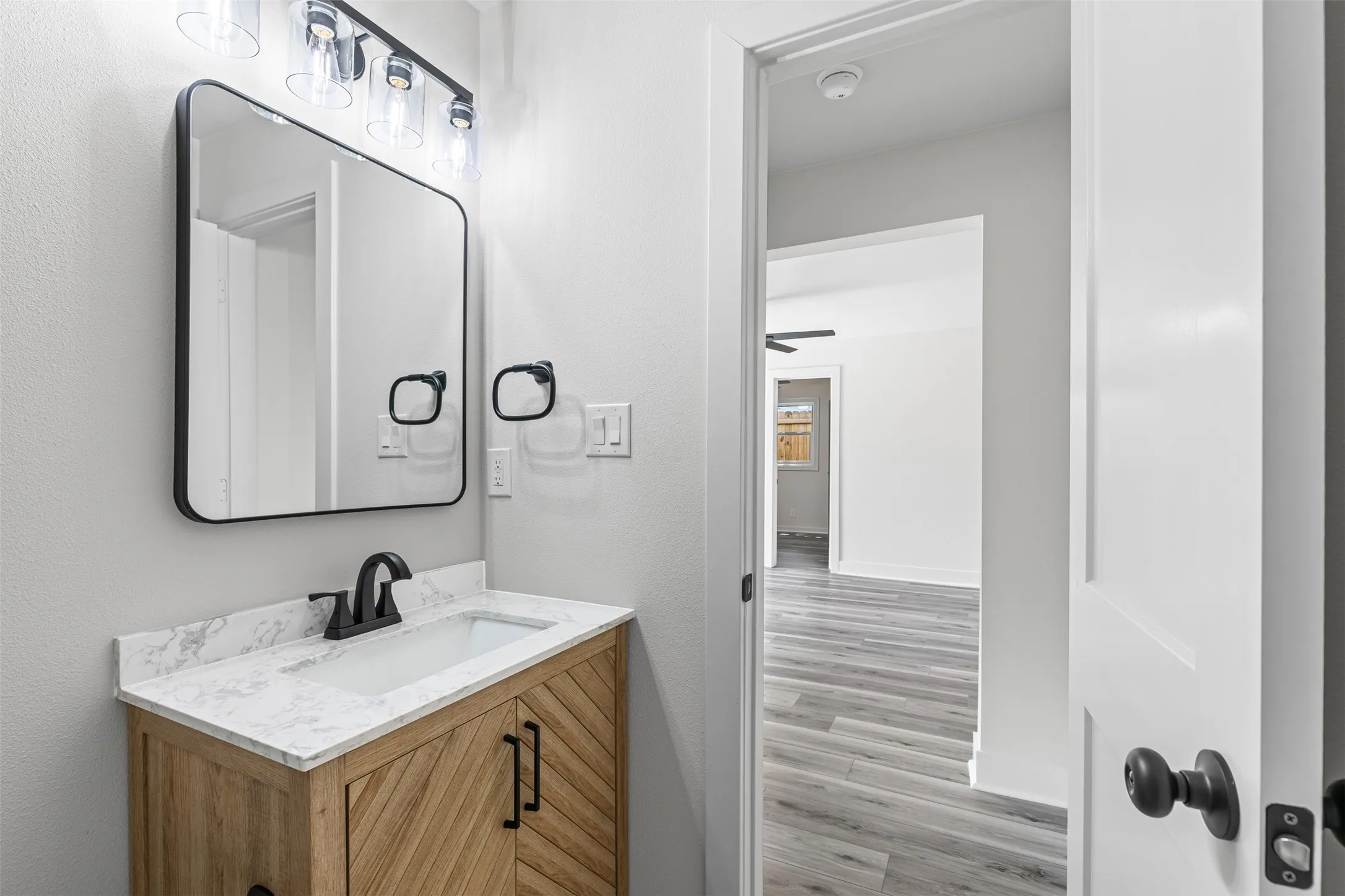 Half bath with vanity, light wood-style flooring, and a ceiling fan