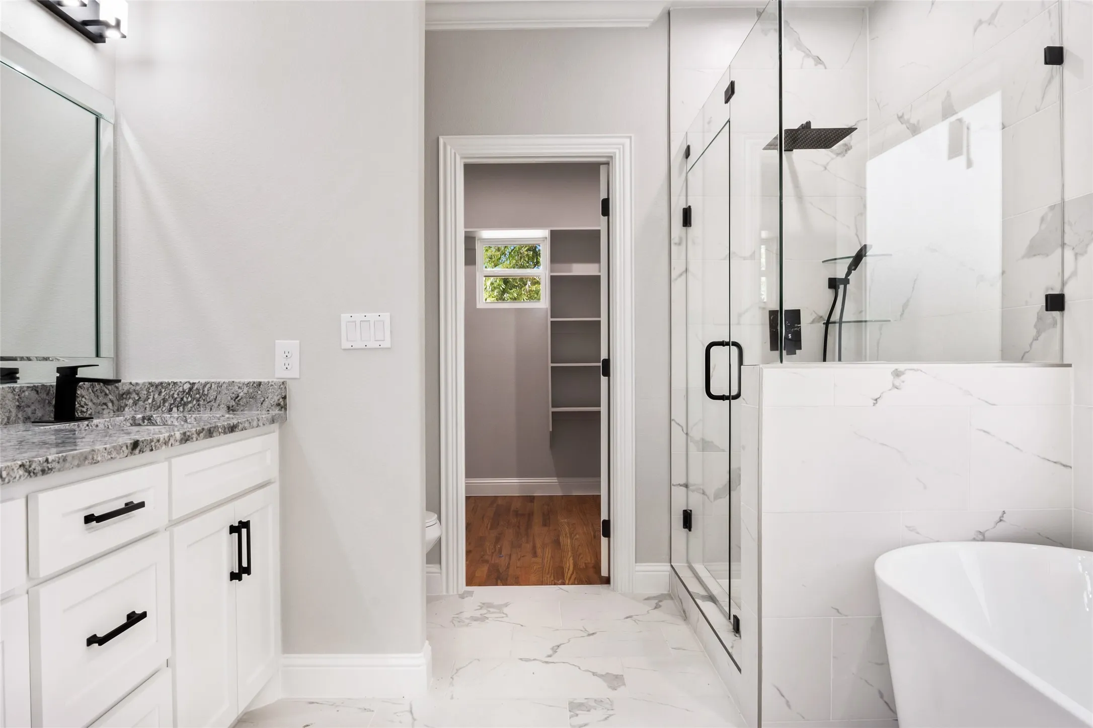 Full bath with custom granite vanity, freestanding bath, modern chic finish shower, and a spacious walk-in closet