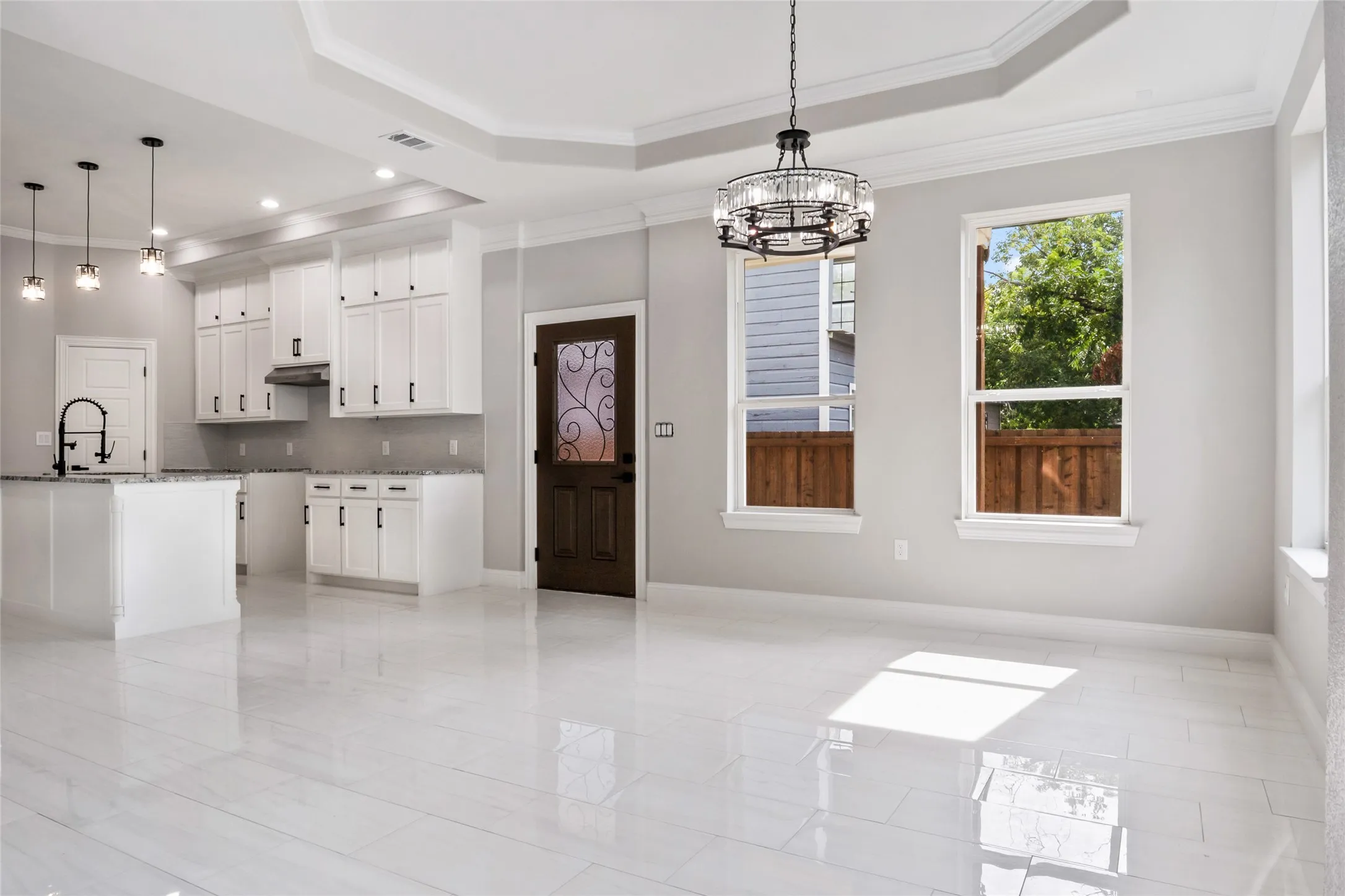 Kitchen featuring ornamental molding, a raised ceiling, a chandelier, backsplash, and white cabinets