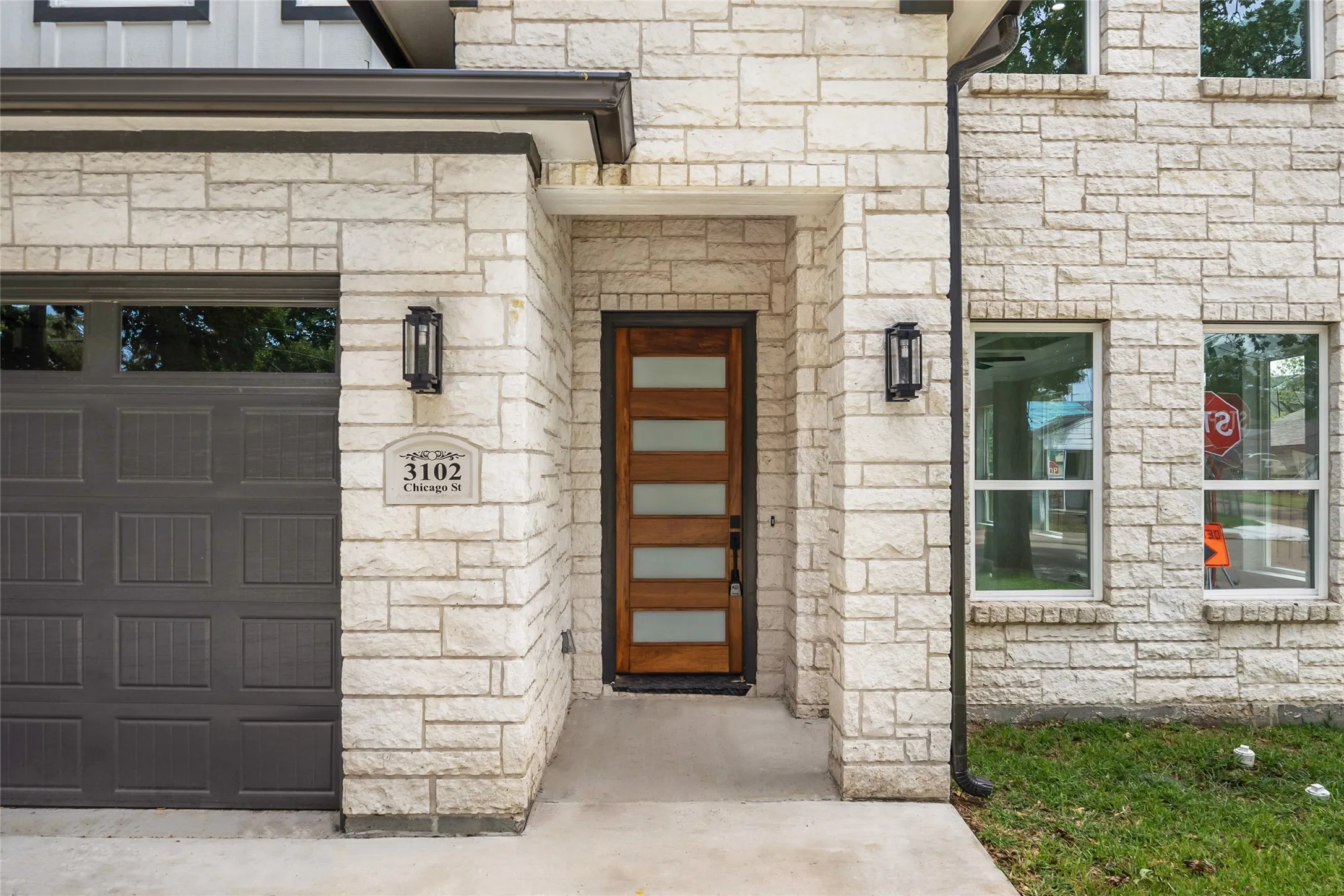 View of exterior entry featuring custom stone siding, a garage, and custom cement board siding