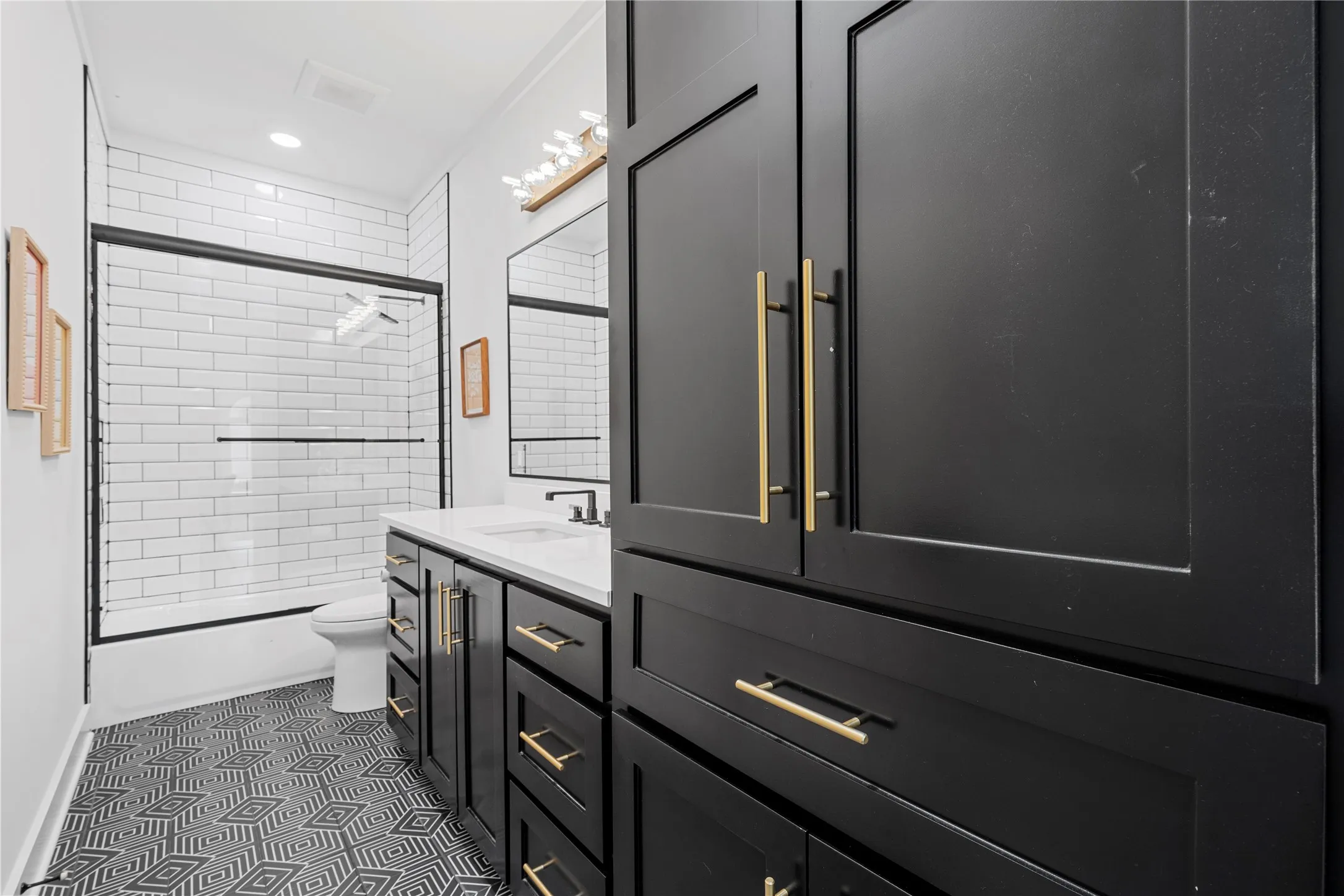 Full bath with vanity, dark tile patterned floors, and tiled shower / bath