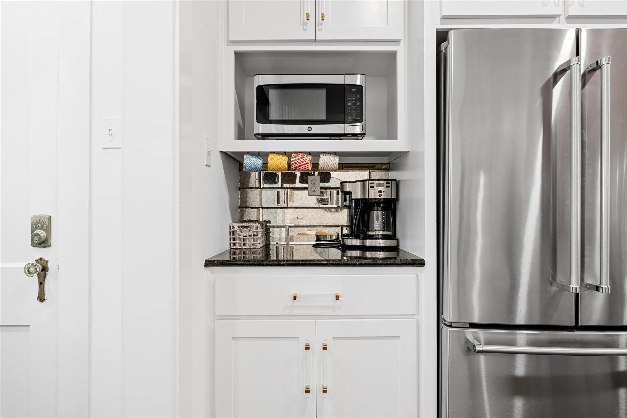 Kitchen featuring appliances with stainless steel finishes, white cabinets, and dark stone countertops