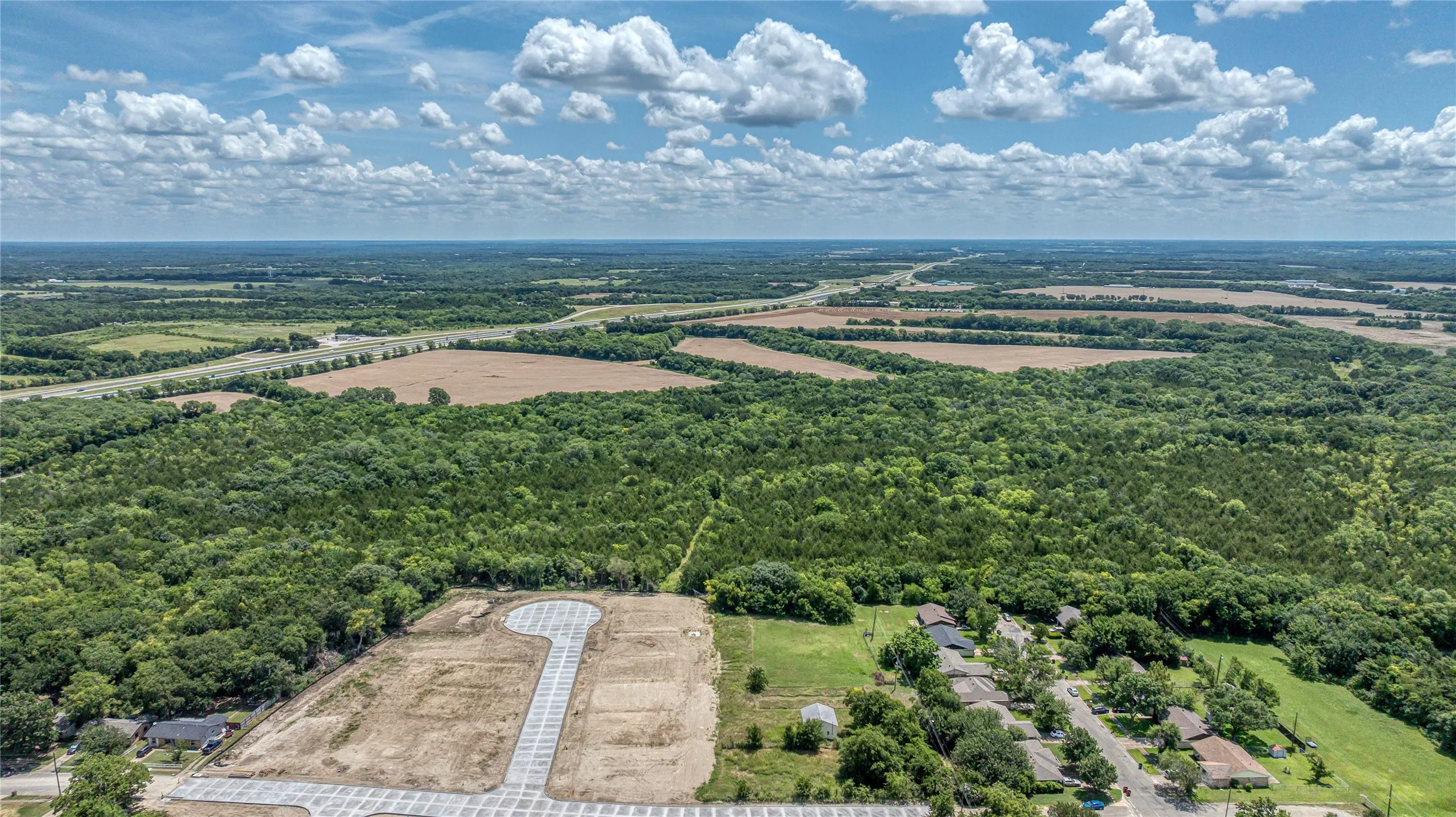 Overview of rural landscape featuring a heavily wooded area and farmland