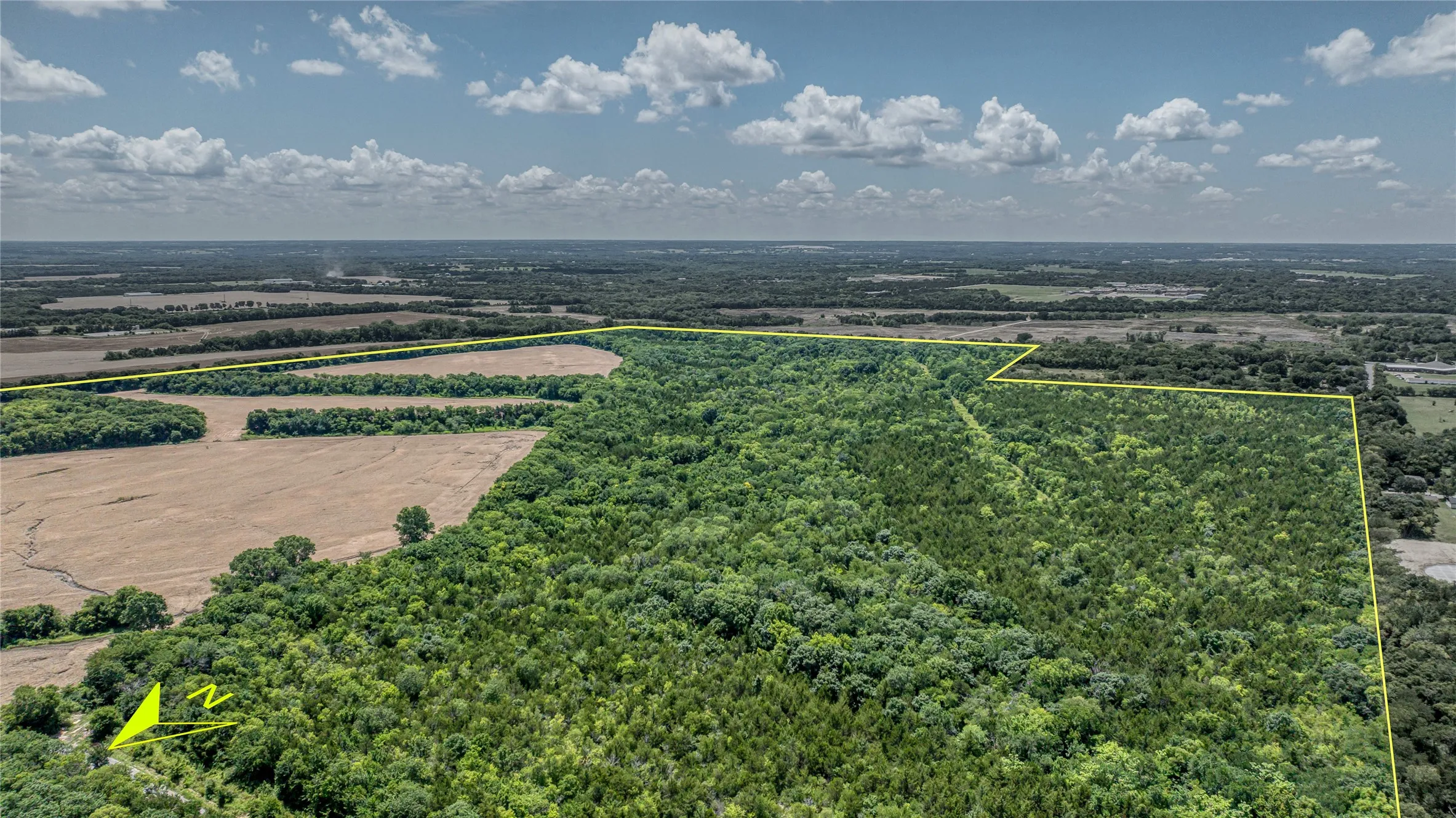 Aerial view of sparsely populated area featuring property boundaries highlighted and a forest