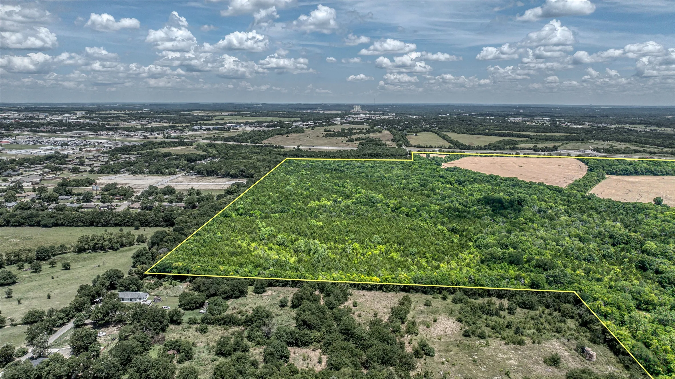 Aerial view of sparsely populated area featuring a forest and property parcel outlined