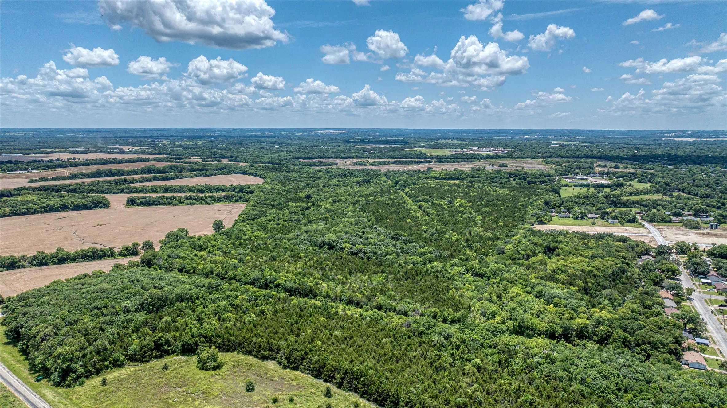 Overview of rural landscape featuring a heavily wooded area