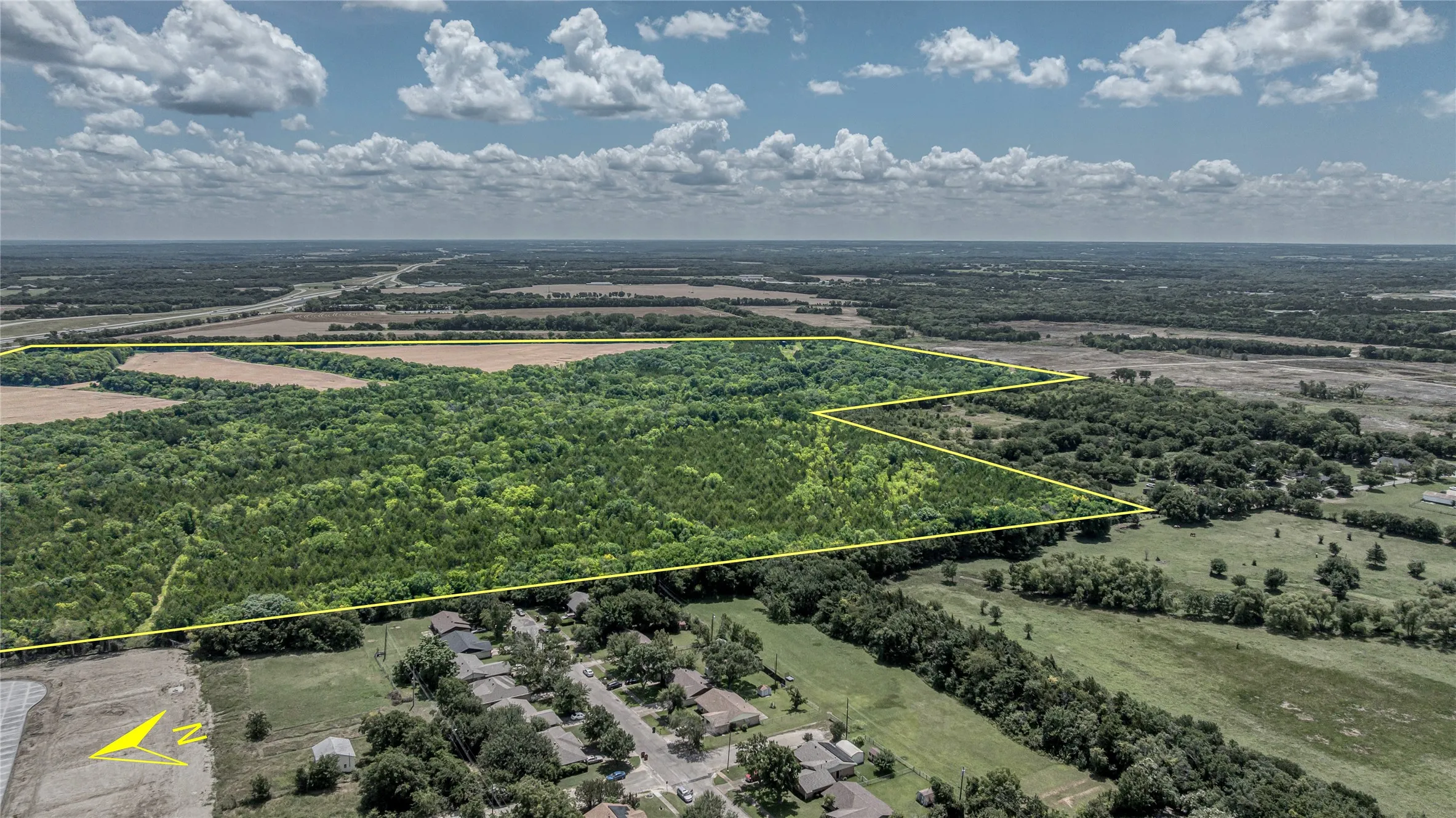 Aerial perspective of suburban area featuring property parcel outlined and a forest