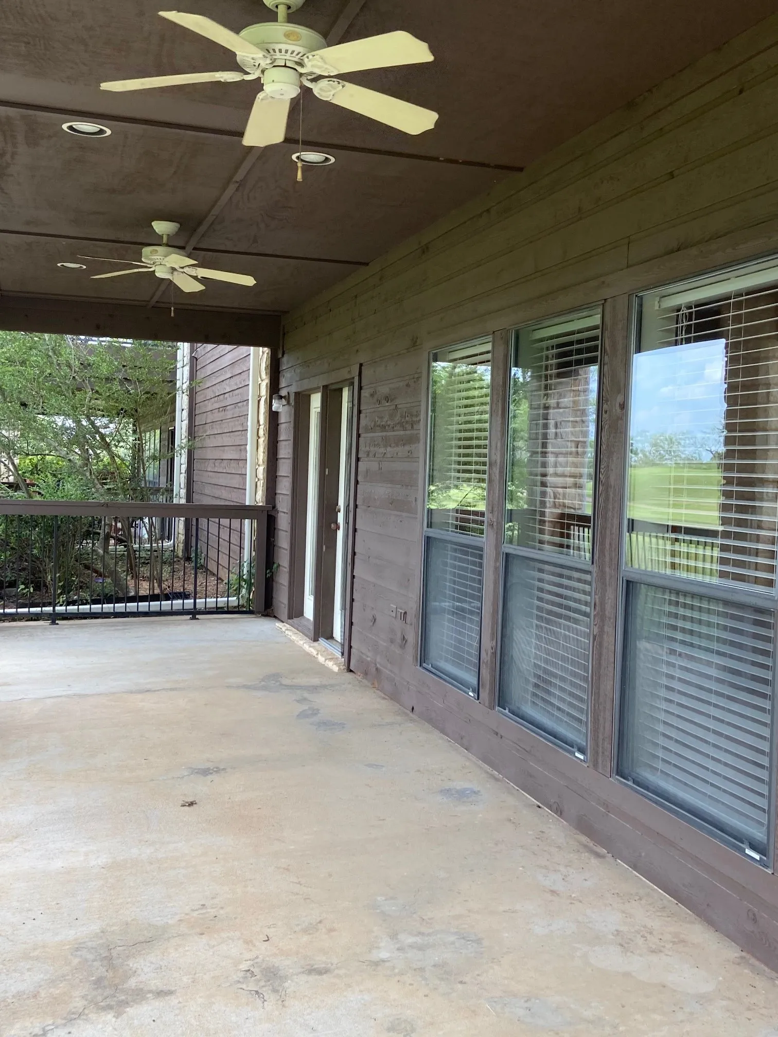 Side view of back patio showing two ceiling fans and windows in back of living area.