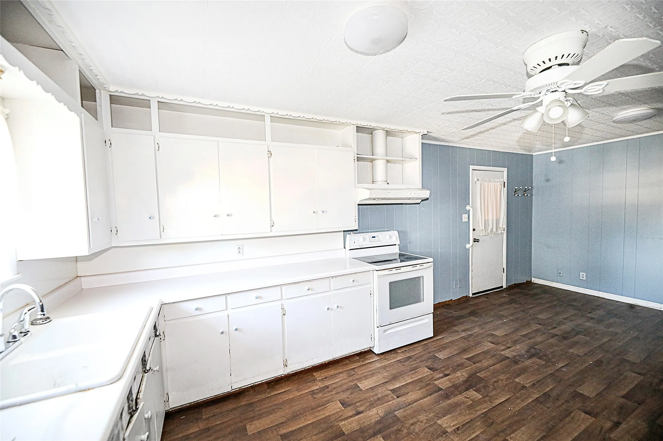 Kitchen with white cabinetry, white electric stove, light countertops, dark wood-type flooring, and open shelves