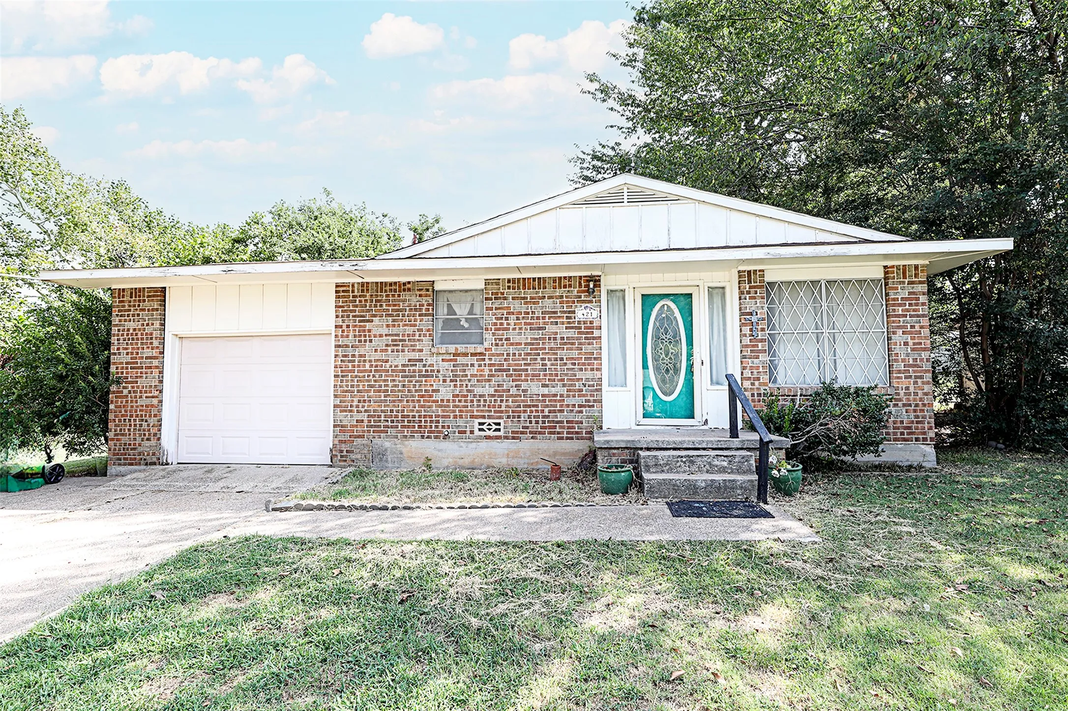 Ranch-style home with an attached garage, a front yard, driveway, board and batten siding, and brick siding