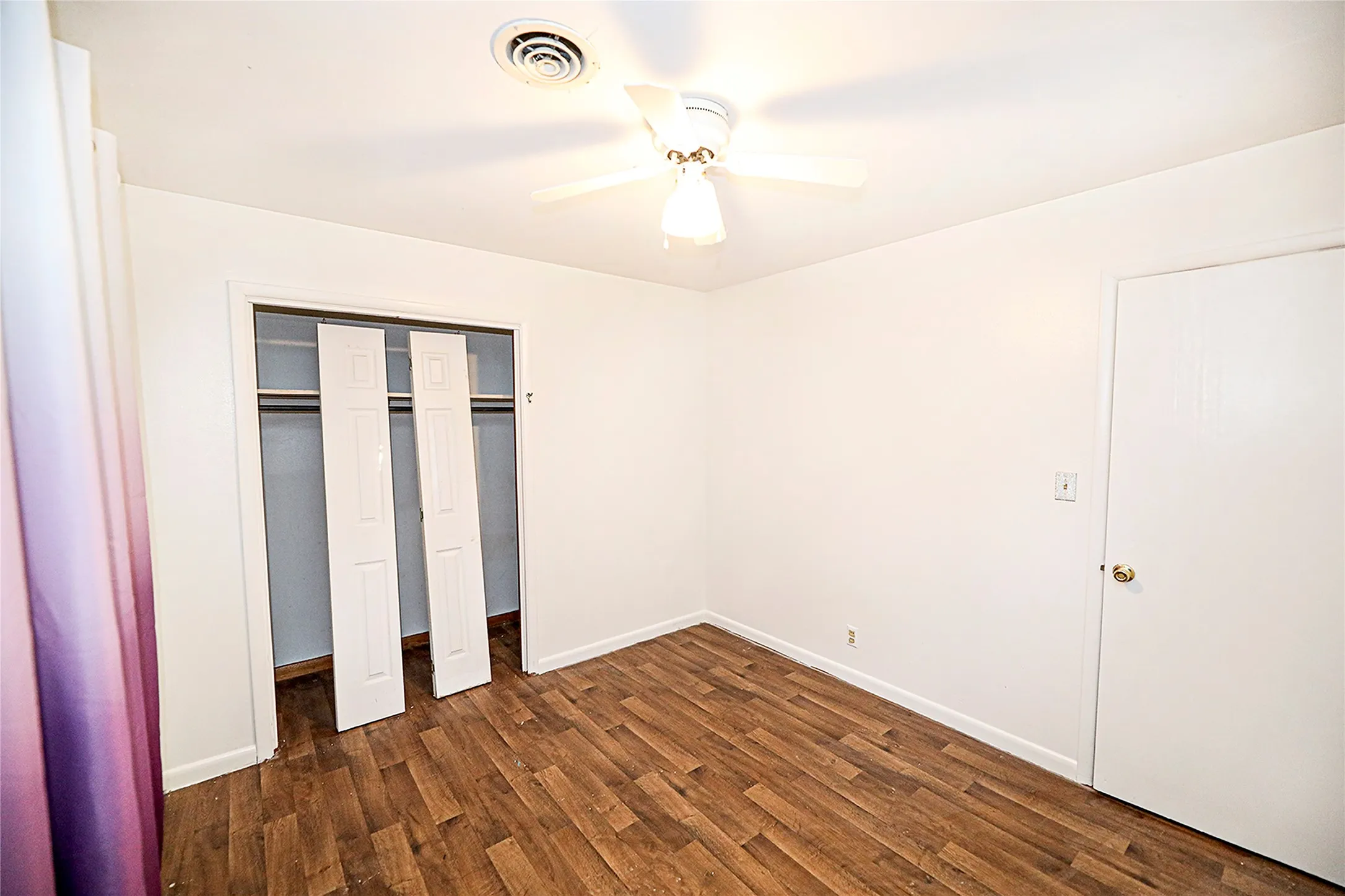 Unfurnished bedroom featuring dark wood-type flooring, a ceiling fan, and a closet