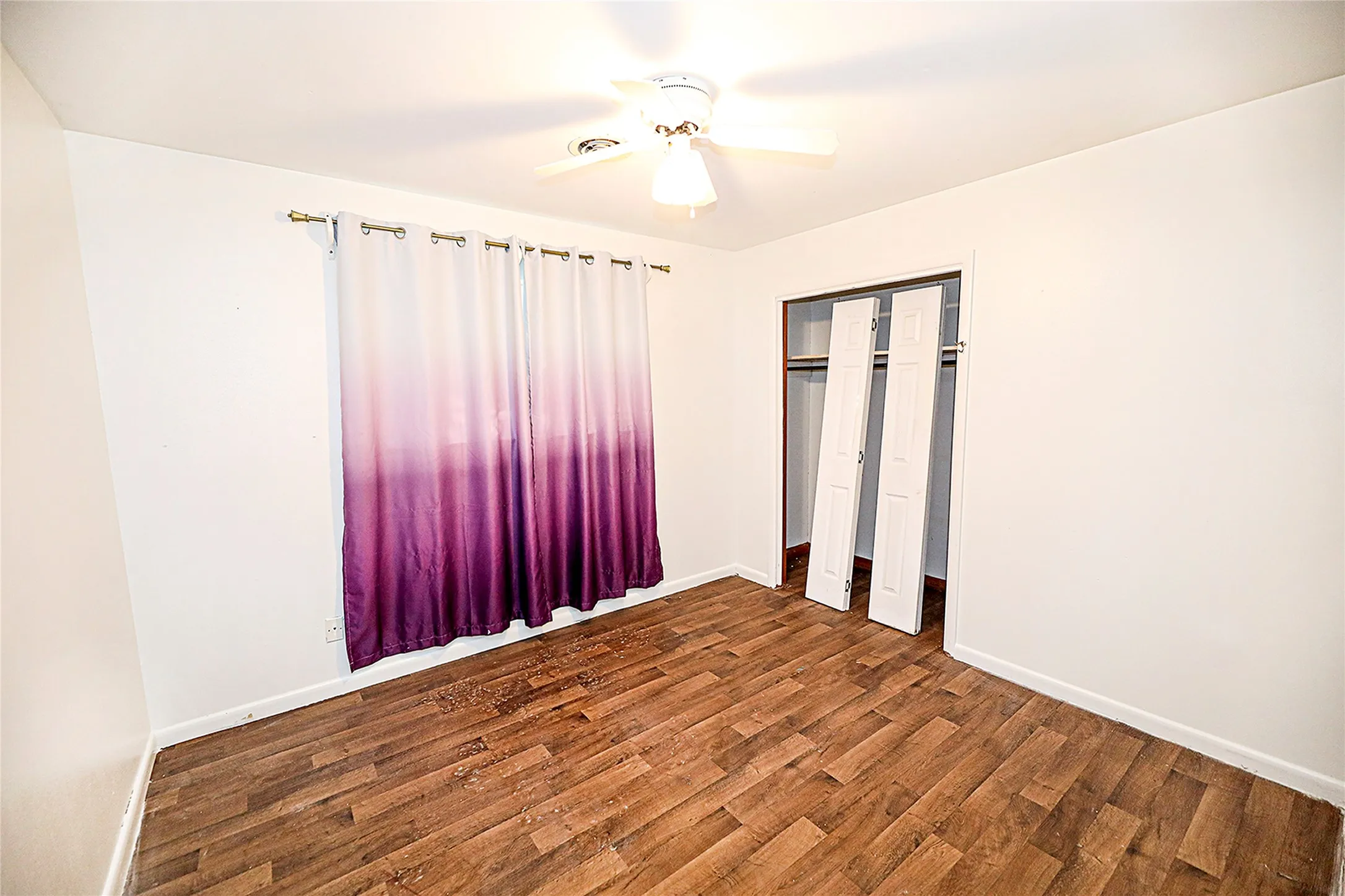 Unfurnished bedroom with dark wood-style floors, ceiling fan, and a closet