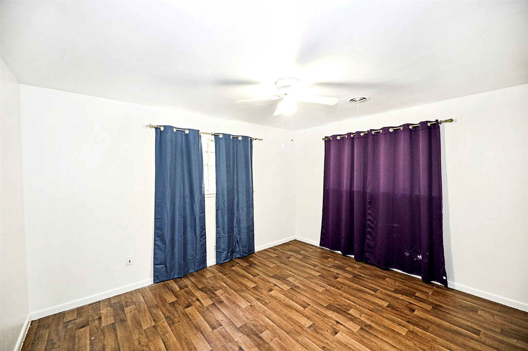 Spare room with dark wood-type flooring and a ceiling fan